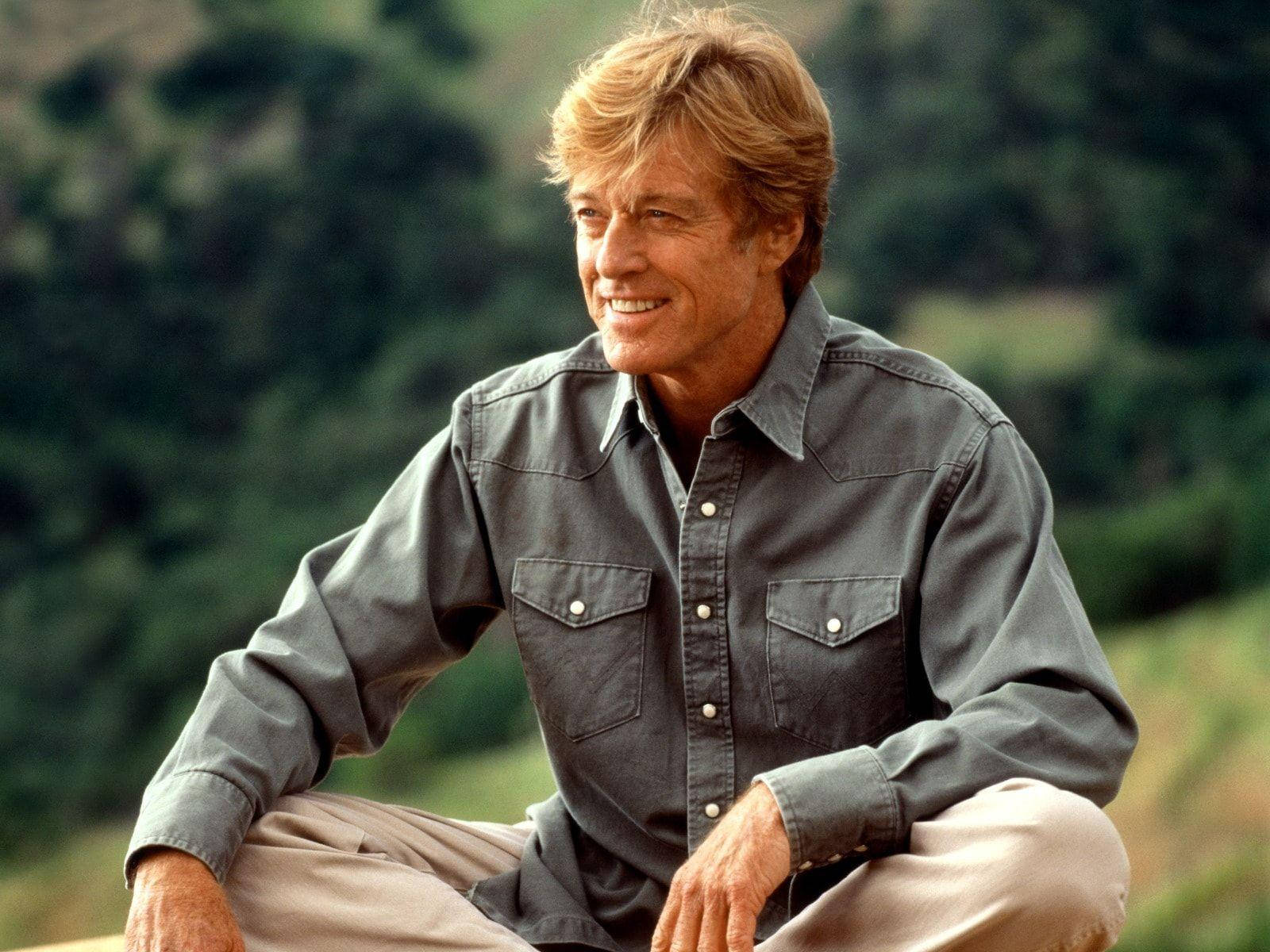Download Robert Redford Smiling And Sitting Wallpaper