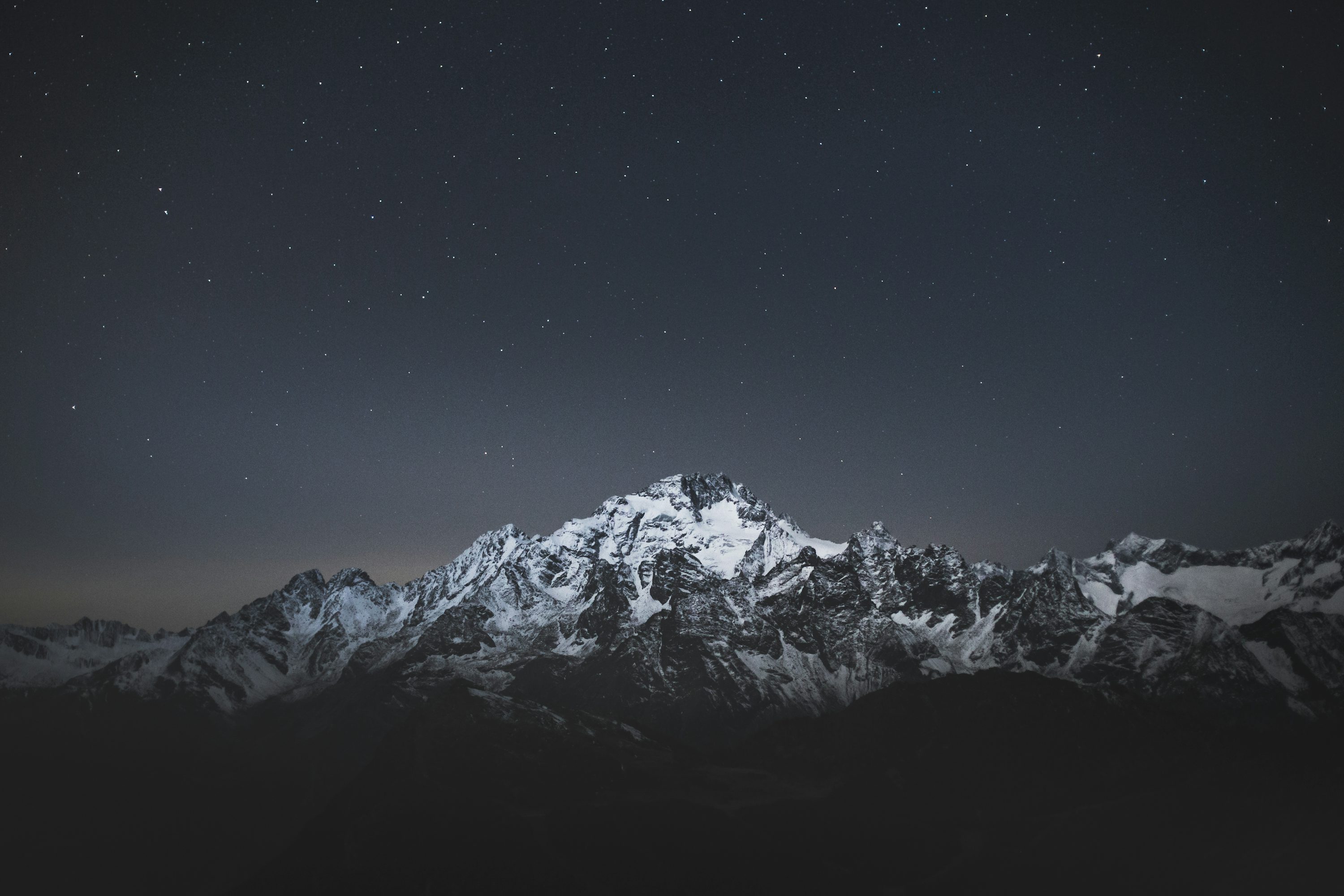Snow covered mountain under blue sky during night time photo