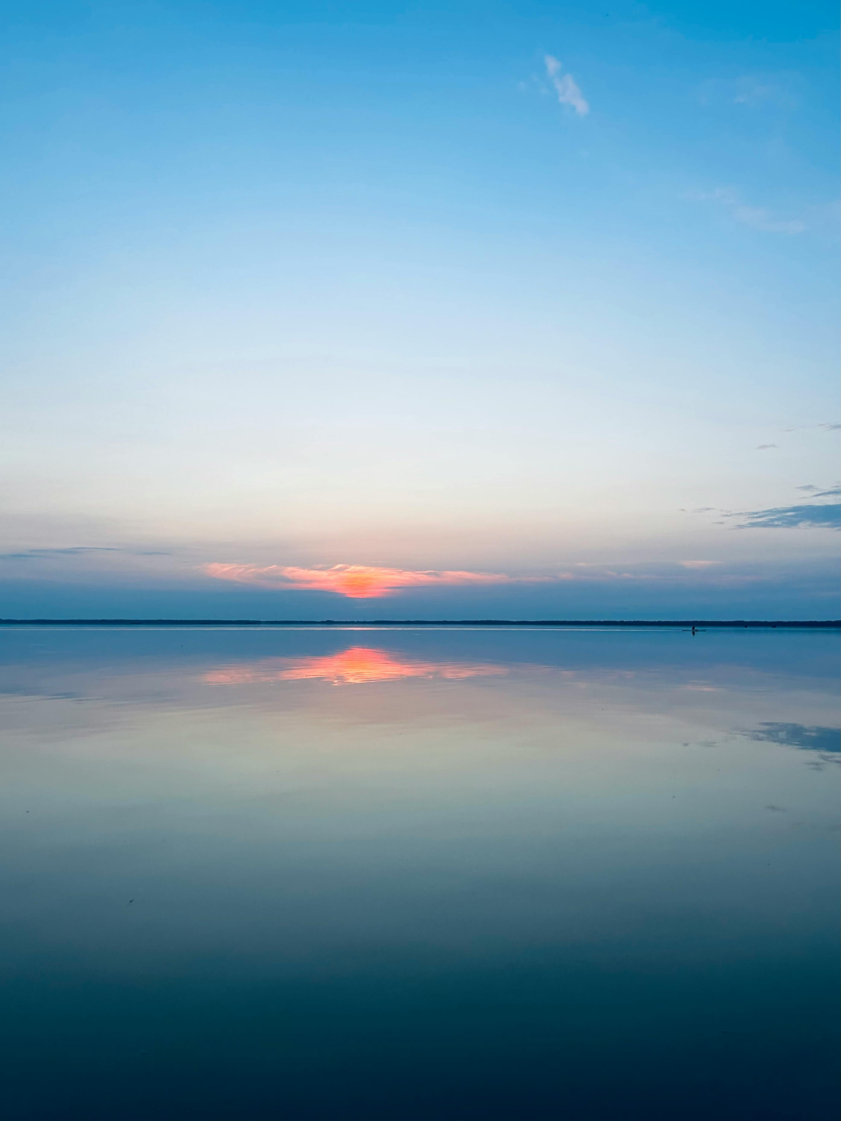 A sunset over a calm lake with a reflection · Free
