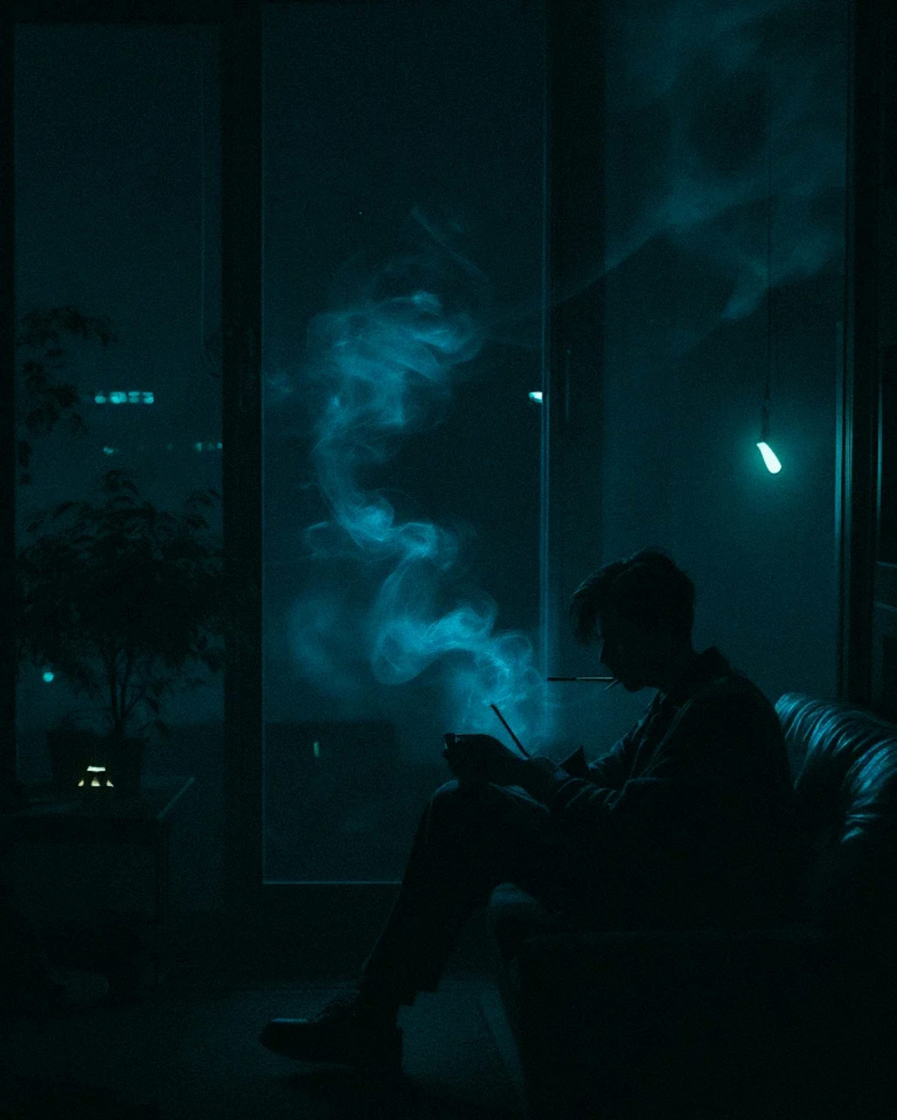 A man sitting on a couch in a dark room photo