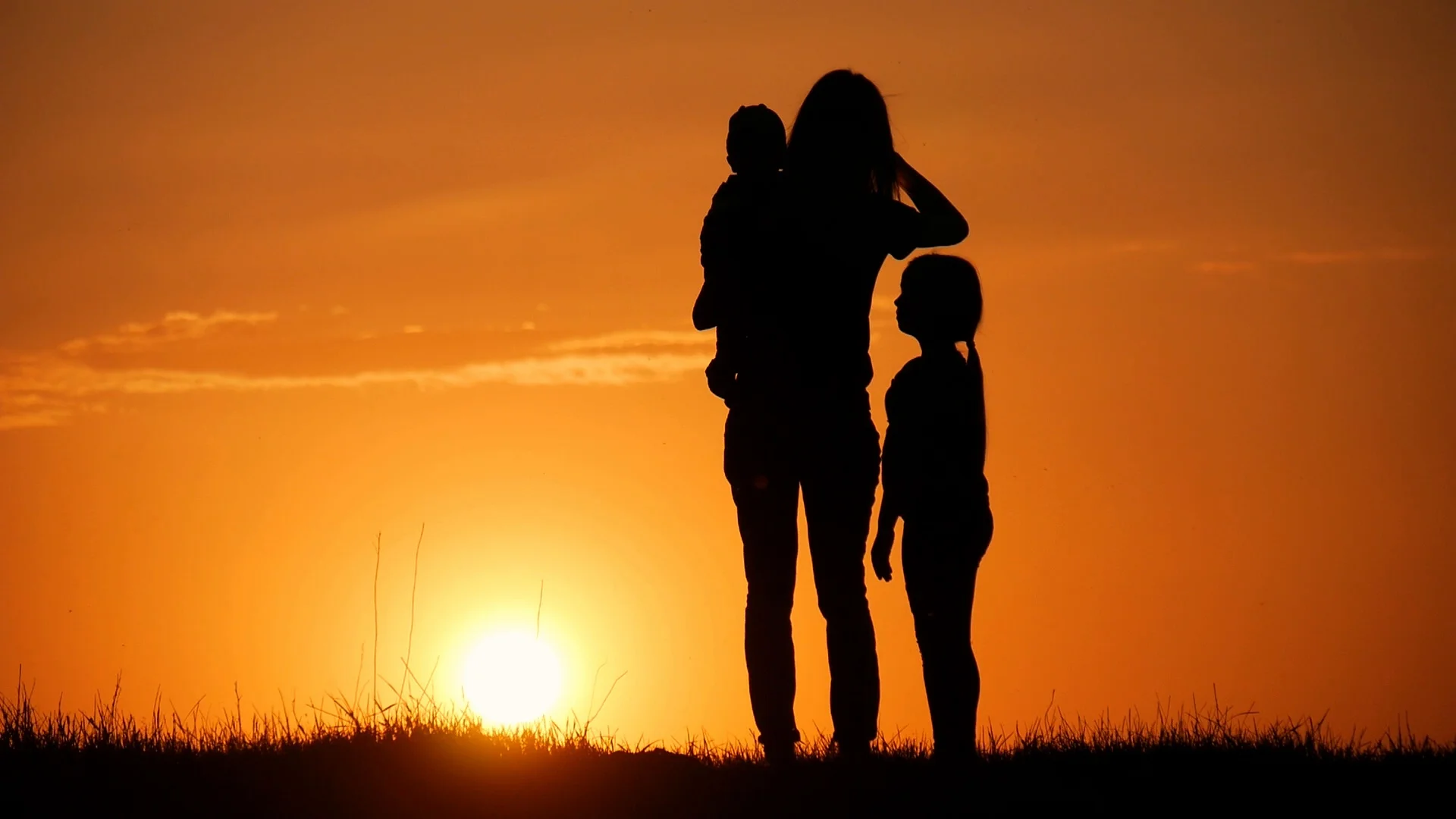 Mother and two kids silhouettes at sunset. Concept of friendly family