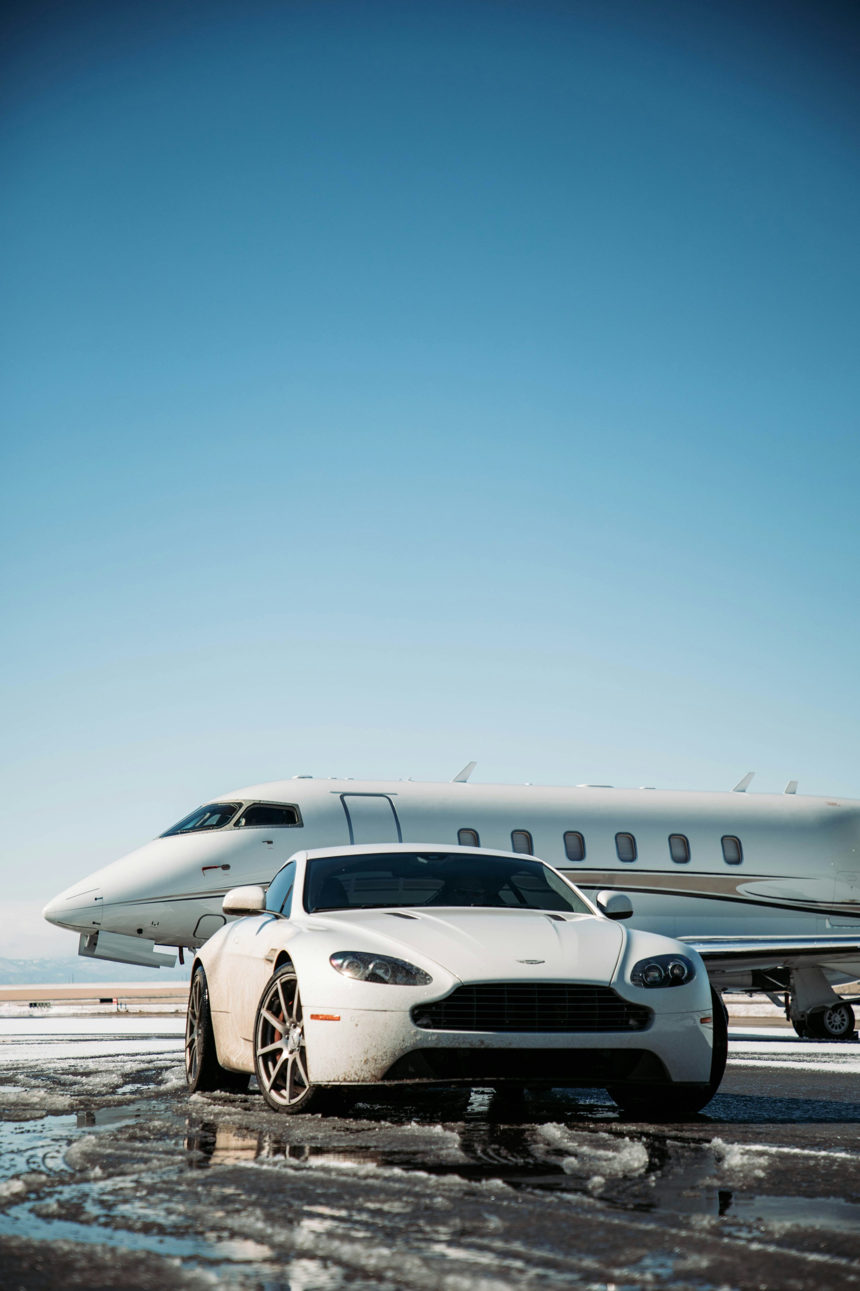A white car is parked in front of a private jet photo