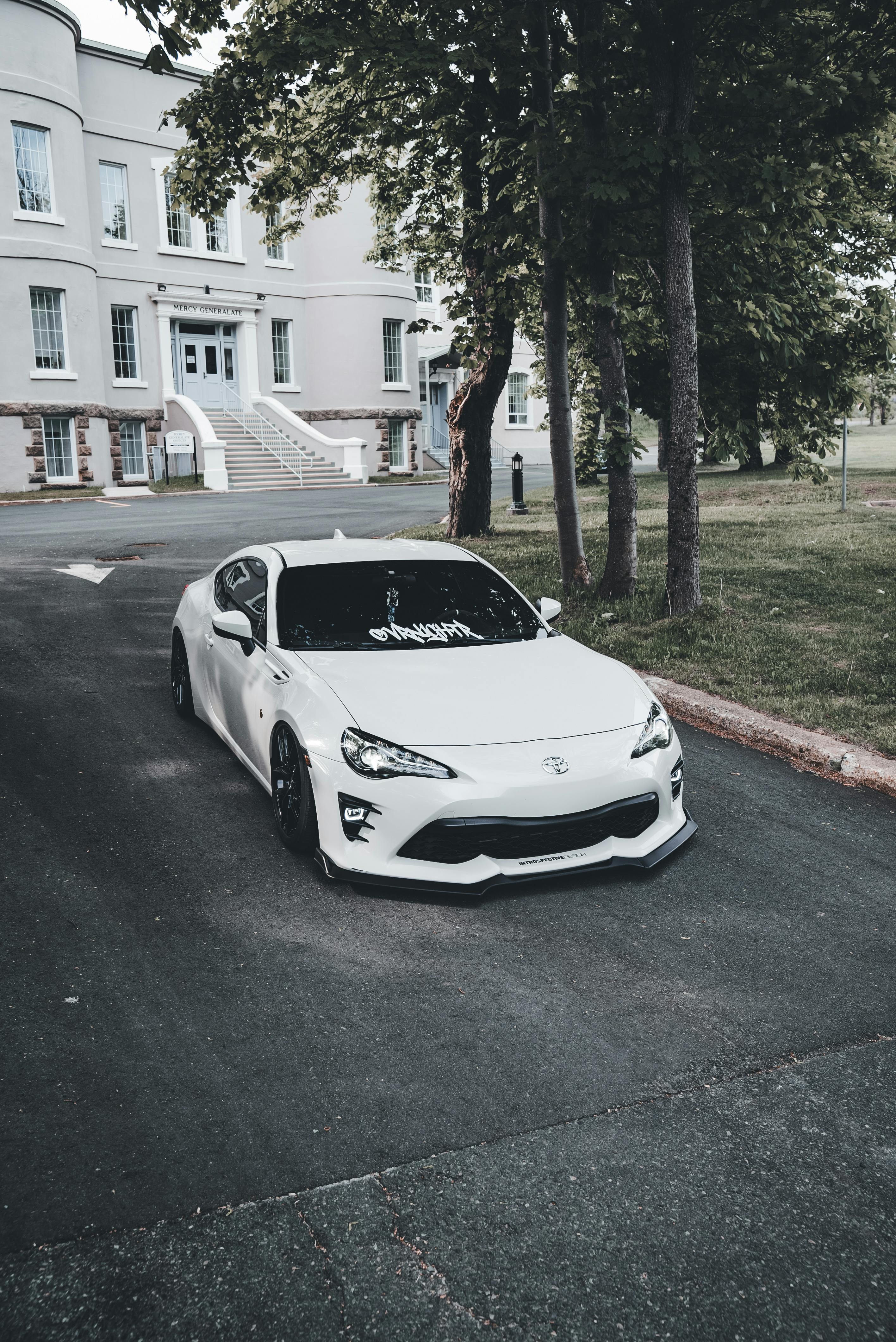 Sleek White Sports Car in Front of Classic Mansion · Free