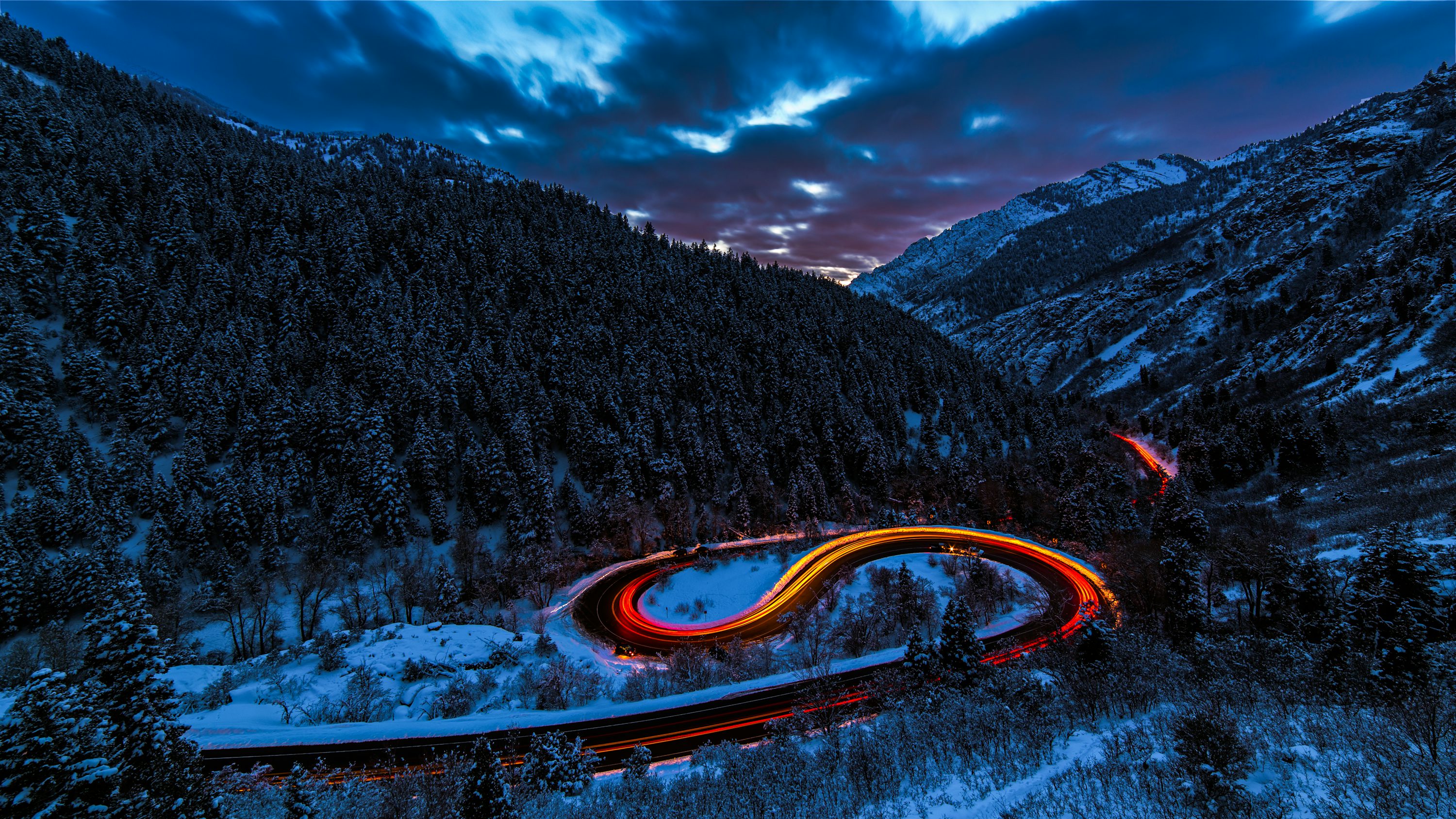 Timelapse photography of curved road between mountain with trees photo