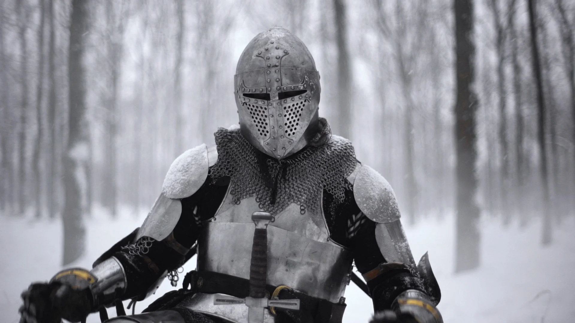 Portrait of medieval knight in helmet holding steel sword and kneeling on winter