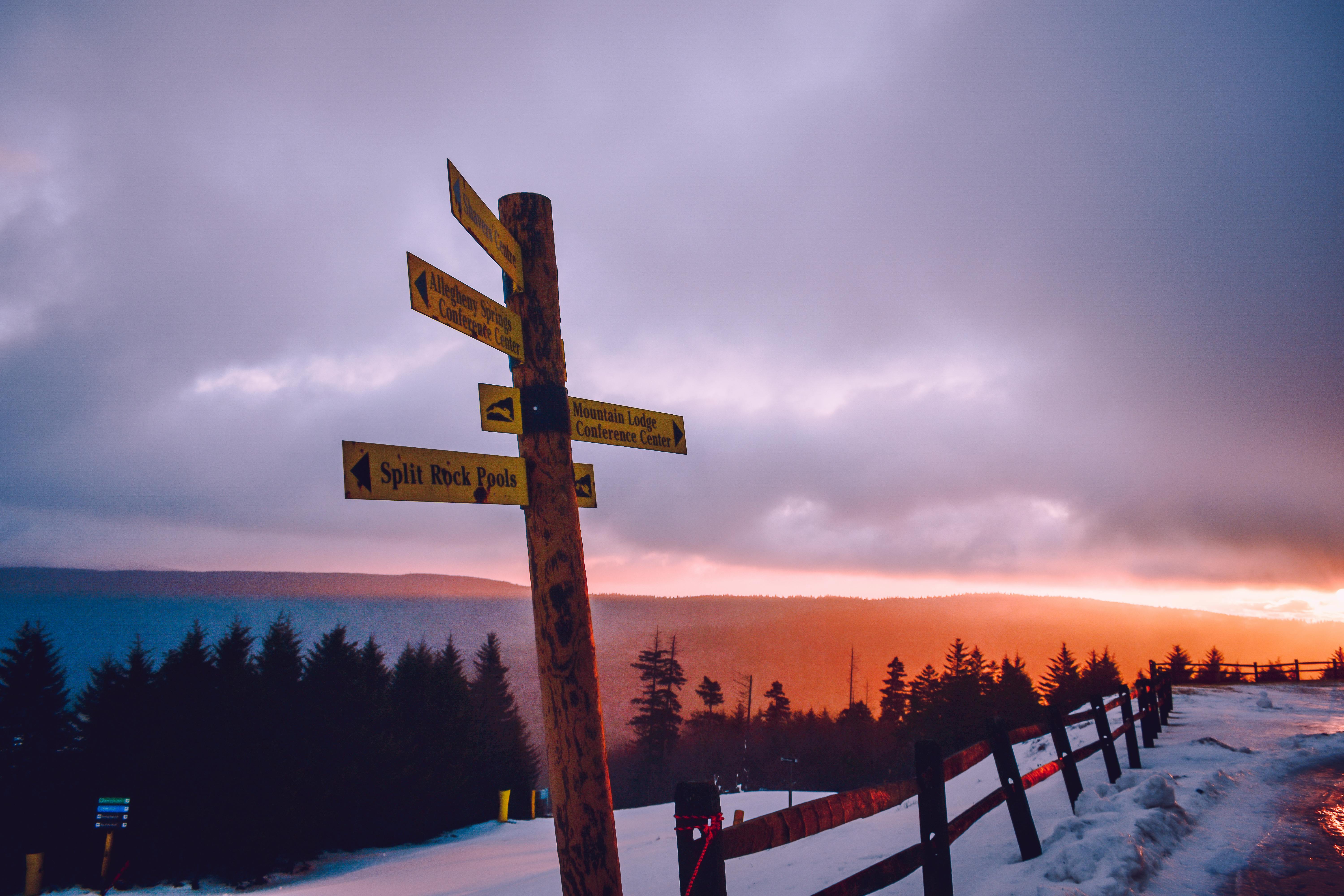 Signpost with tourist routes on snowy roadside · Free