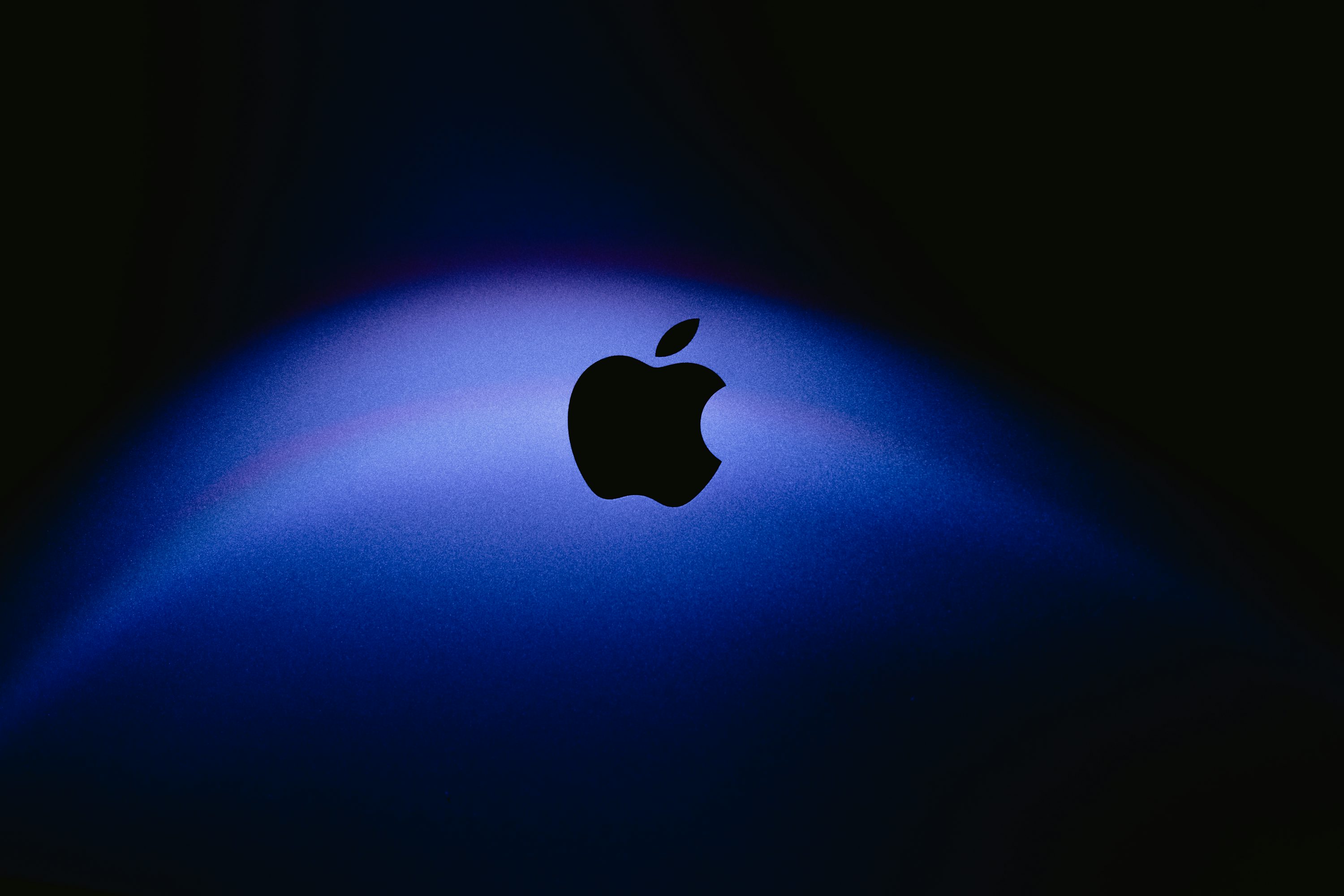 The apple logo is illuminated against a blue background. photo