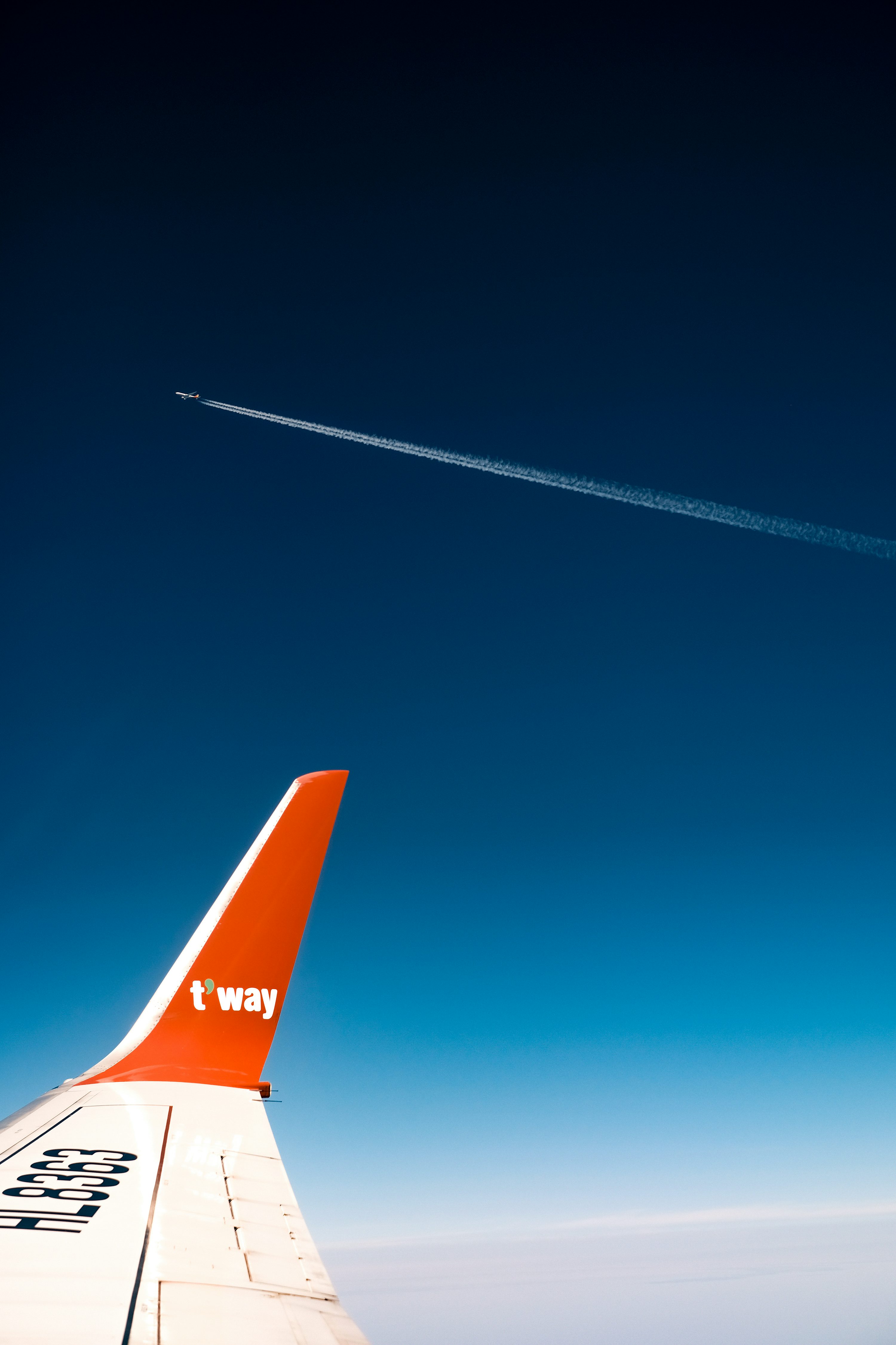 An airplane flying in the sky with a contrail in the sky photo