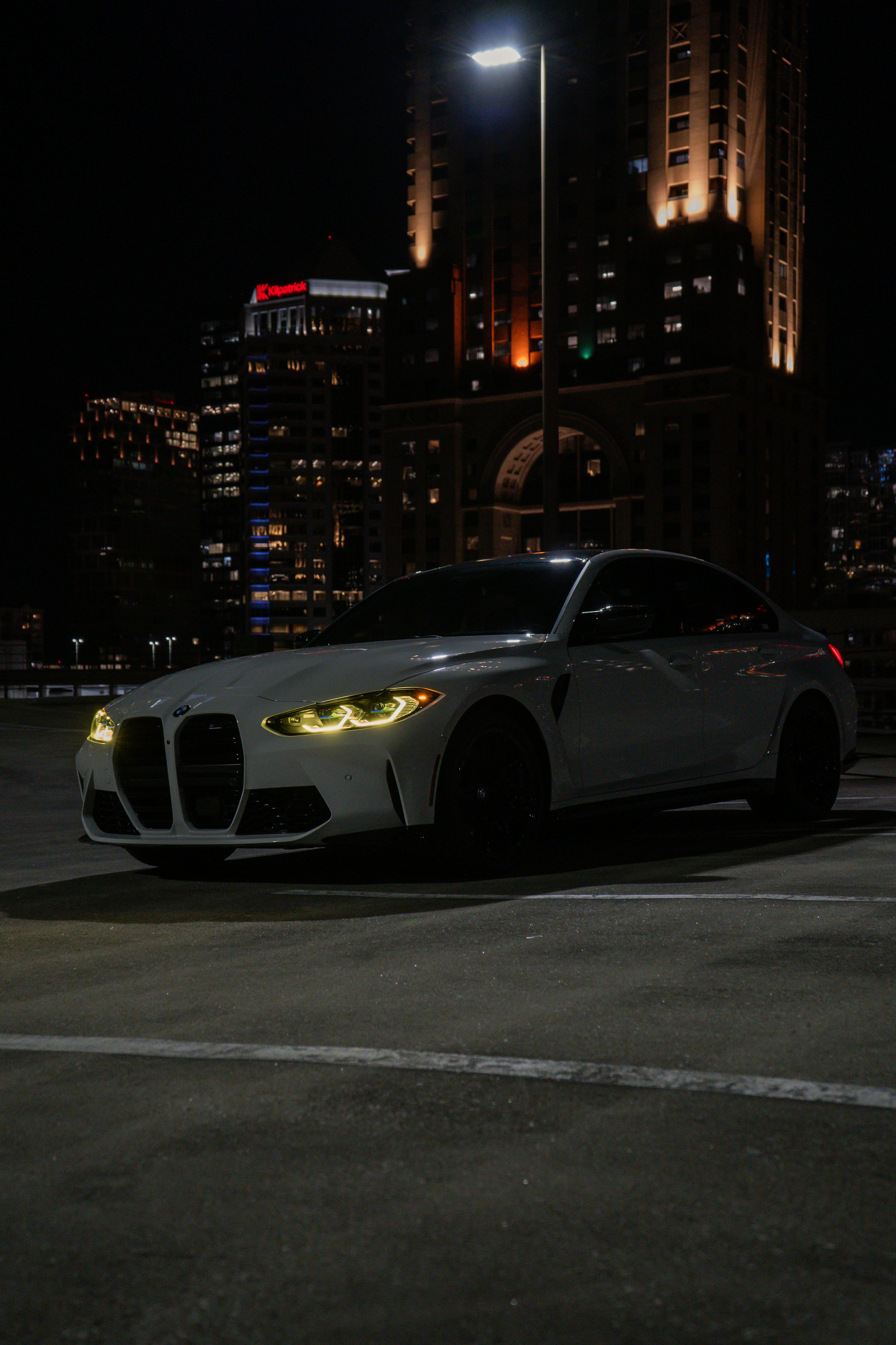 A white BMW m4 is parked at night. photo