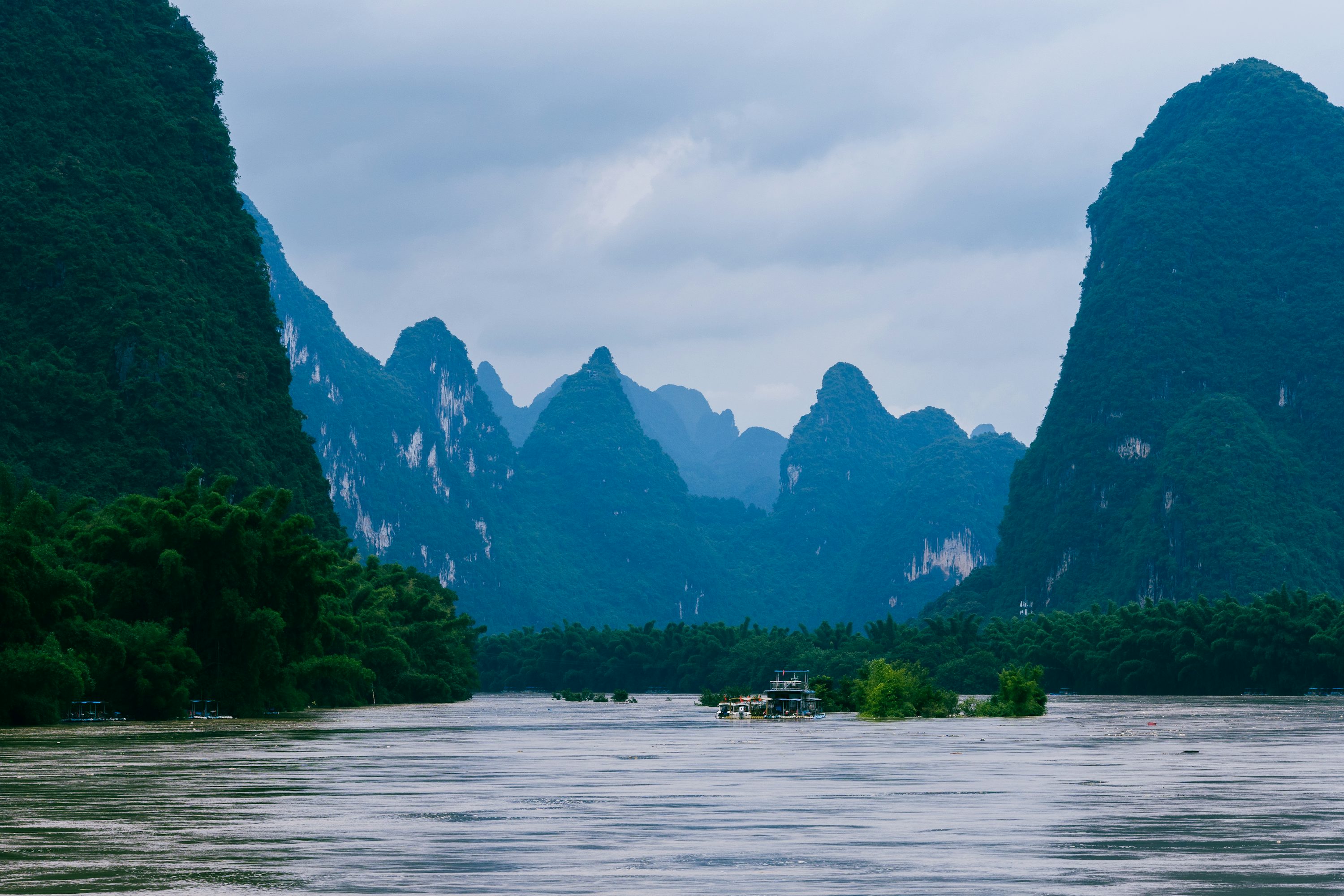 A boat on the water with mountains in the background with Li River in the background photo
