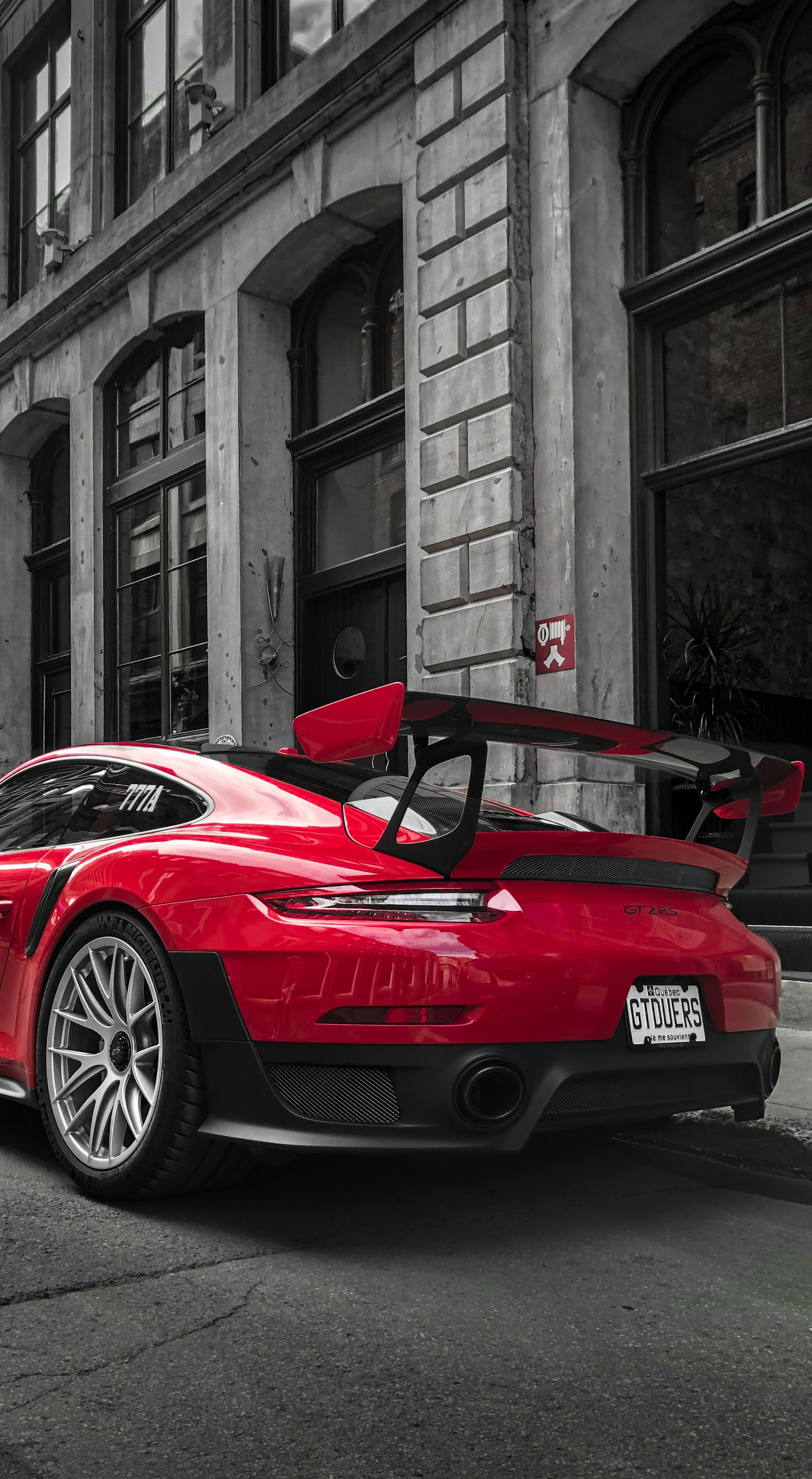 Selective color photography of red Porsche sports car parked at roadside photo