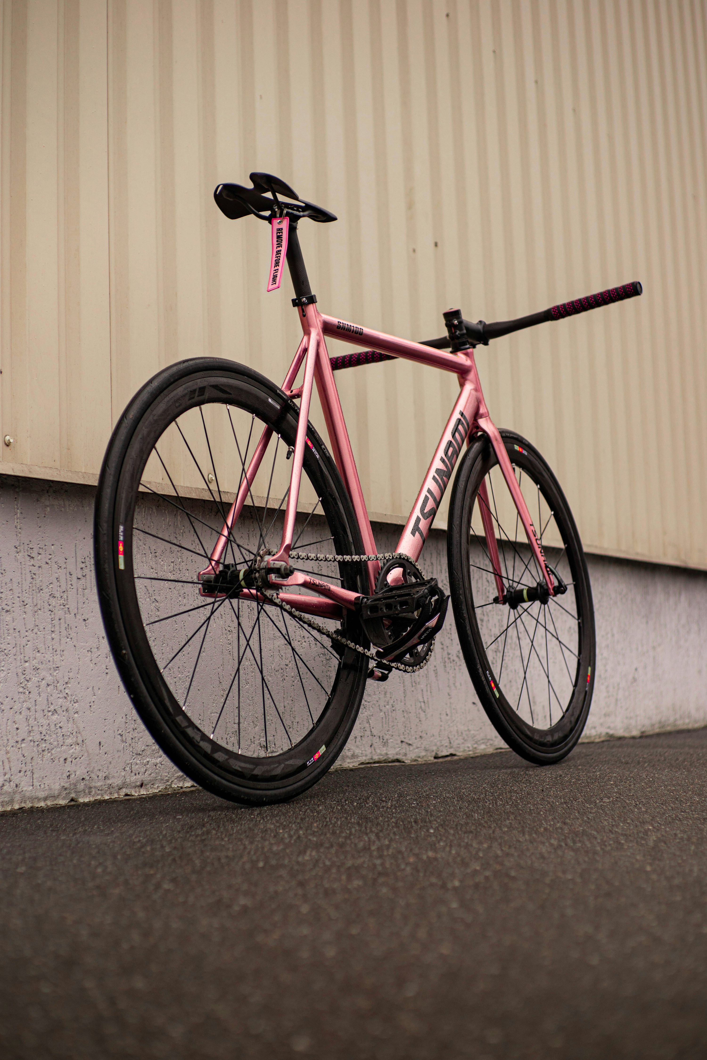 A pink bike parked next to a building photo
