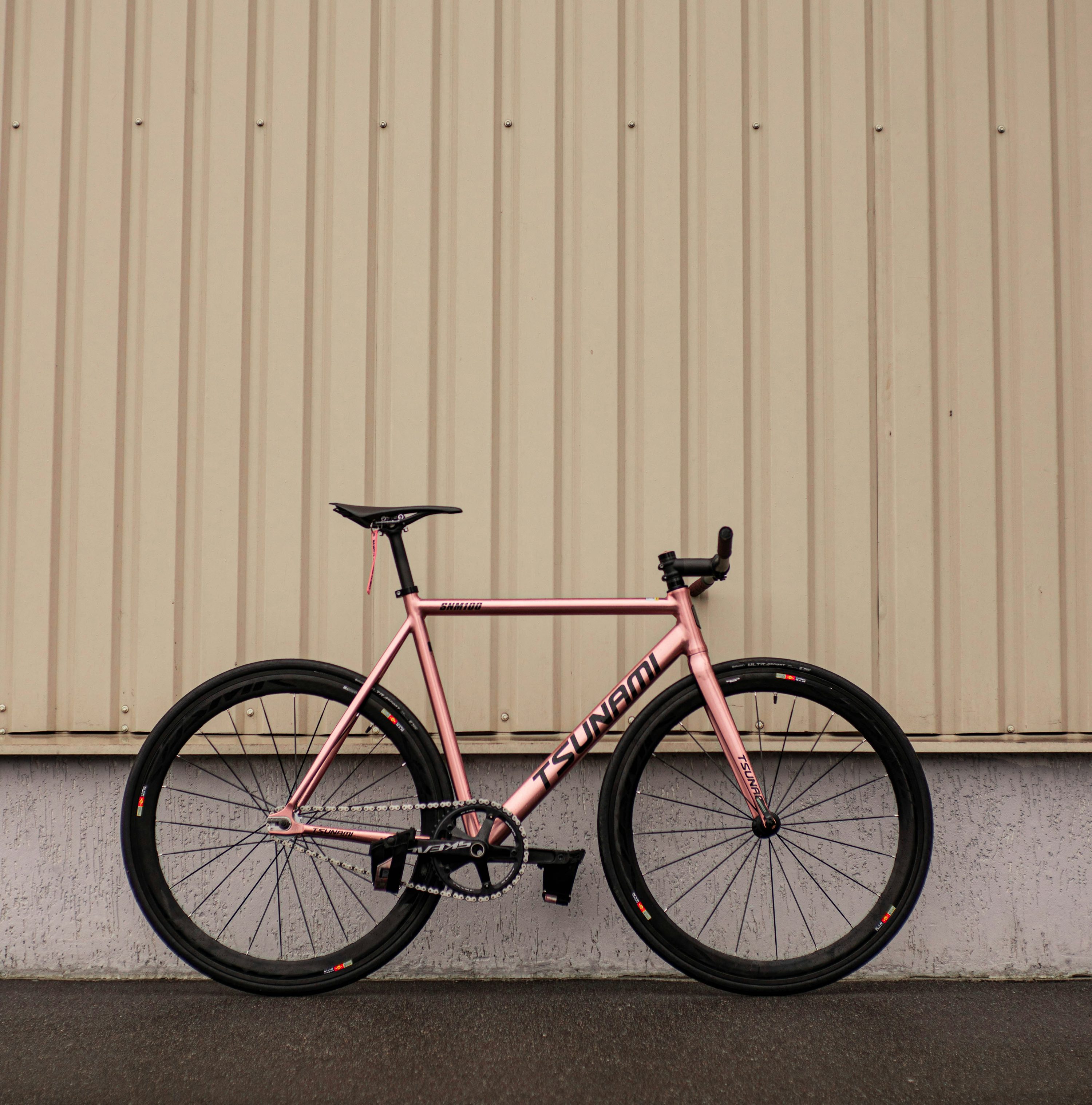 A pink bike parked next to a building photo