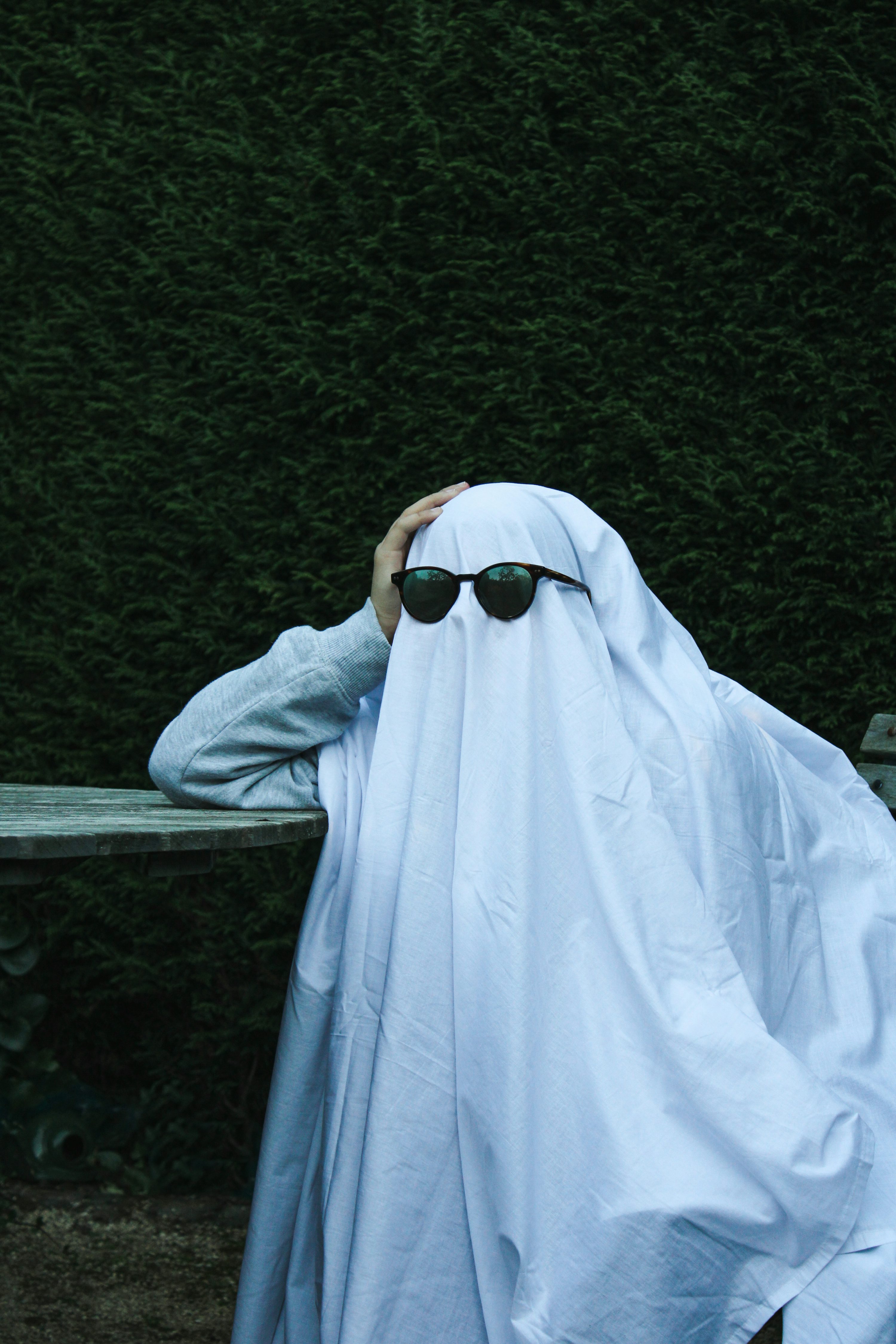 A person with sunglasses covering their face with a blanket photo