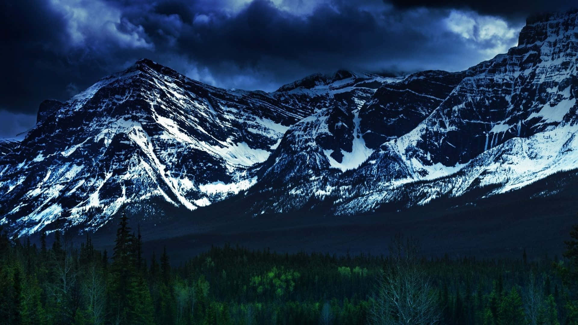 Download A Mountain Range With Trees And A Dark Sky