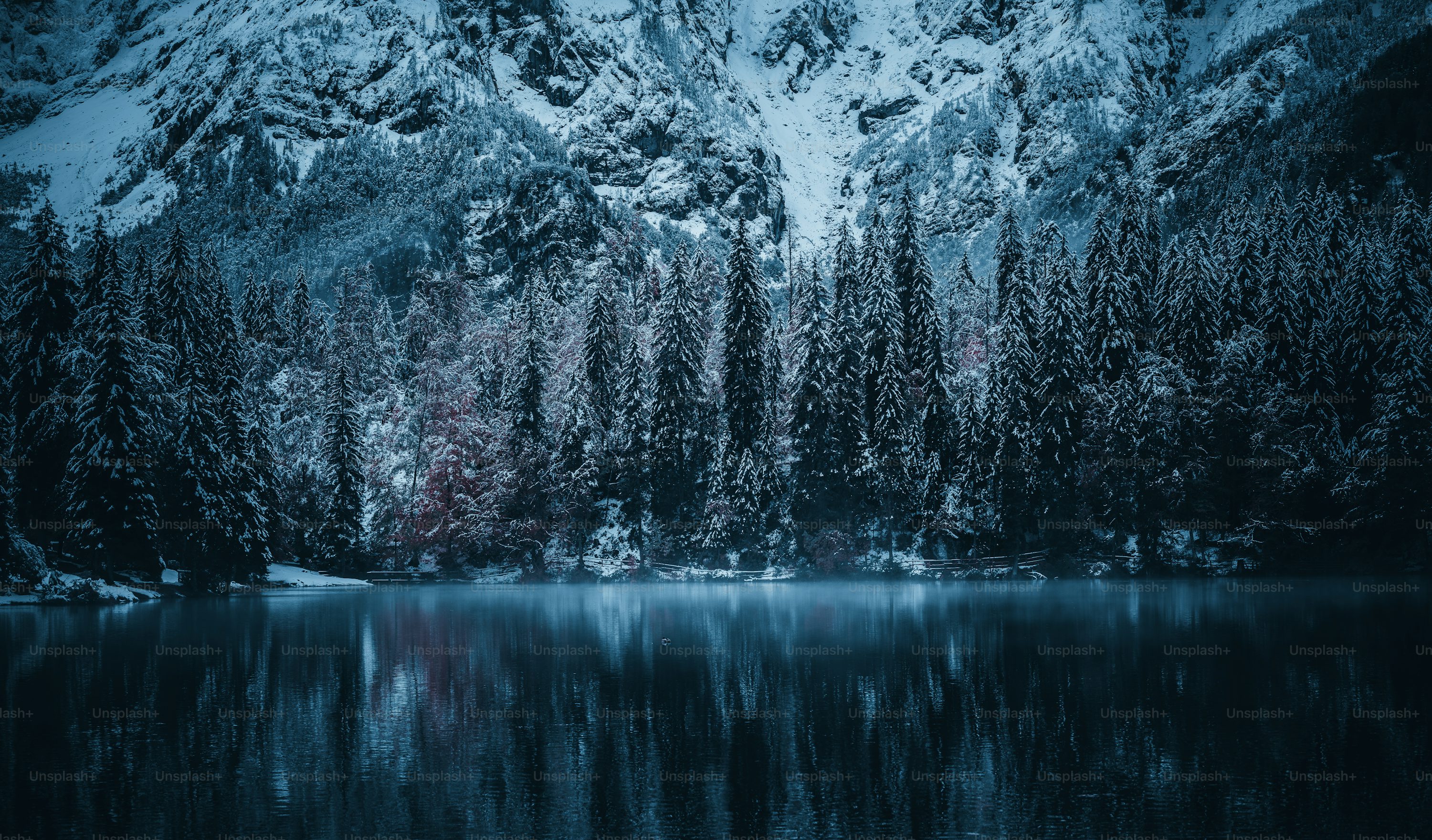 A mountain covered in snow next to a lake photo