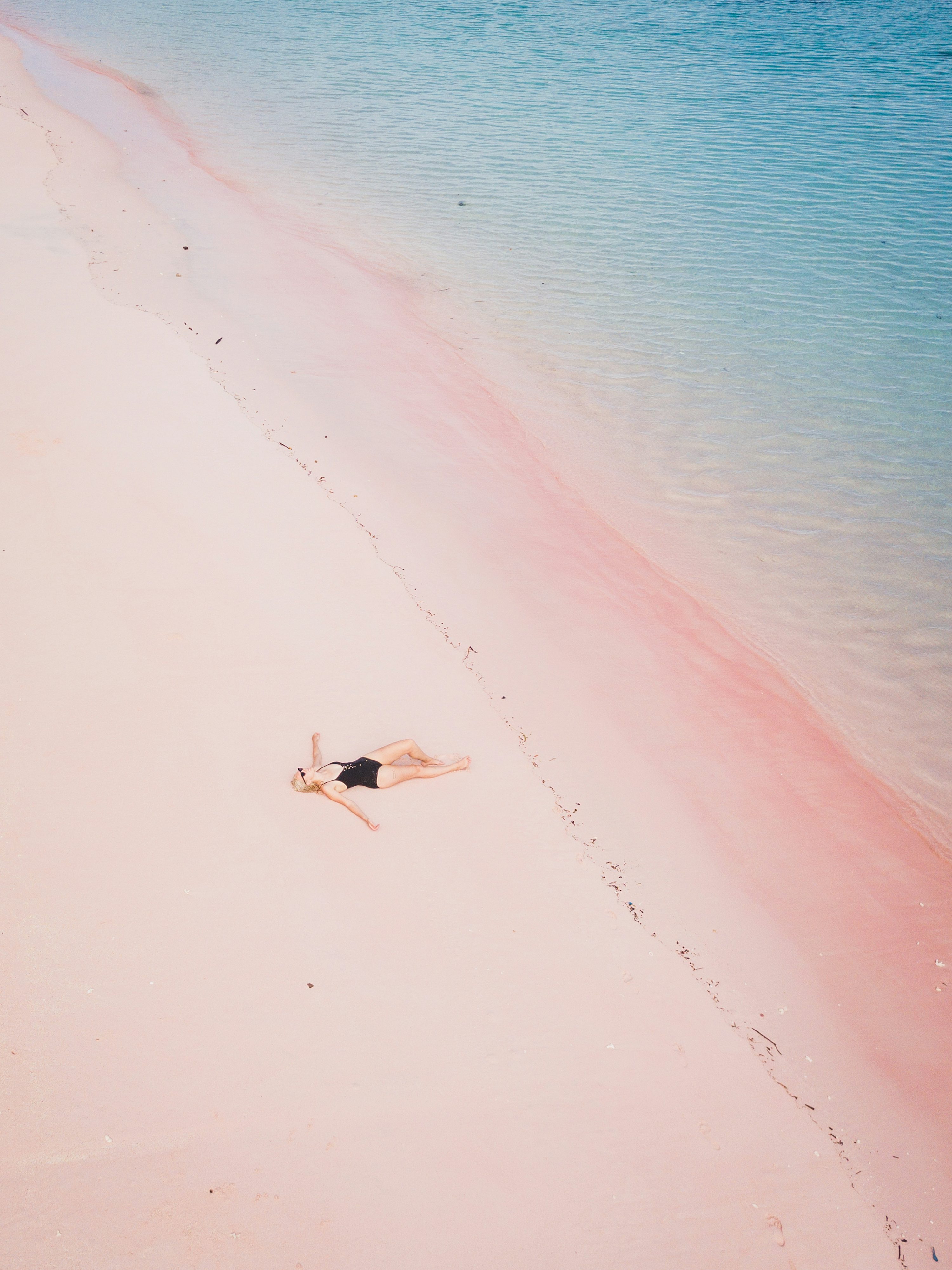 A woman laying on a beach next to a body of water photo