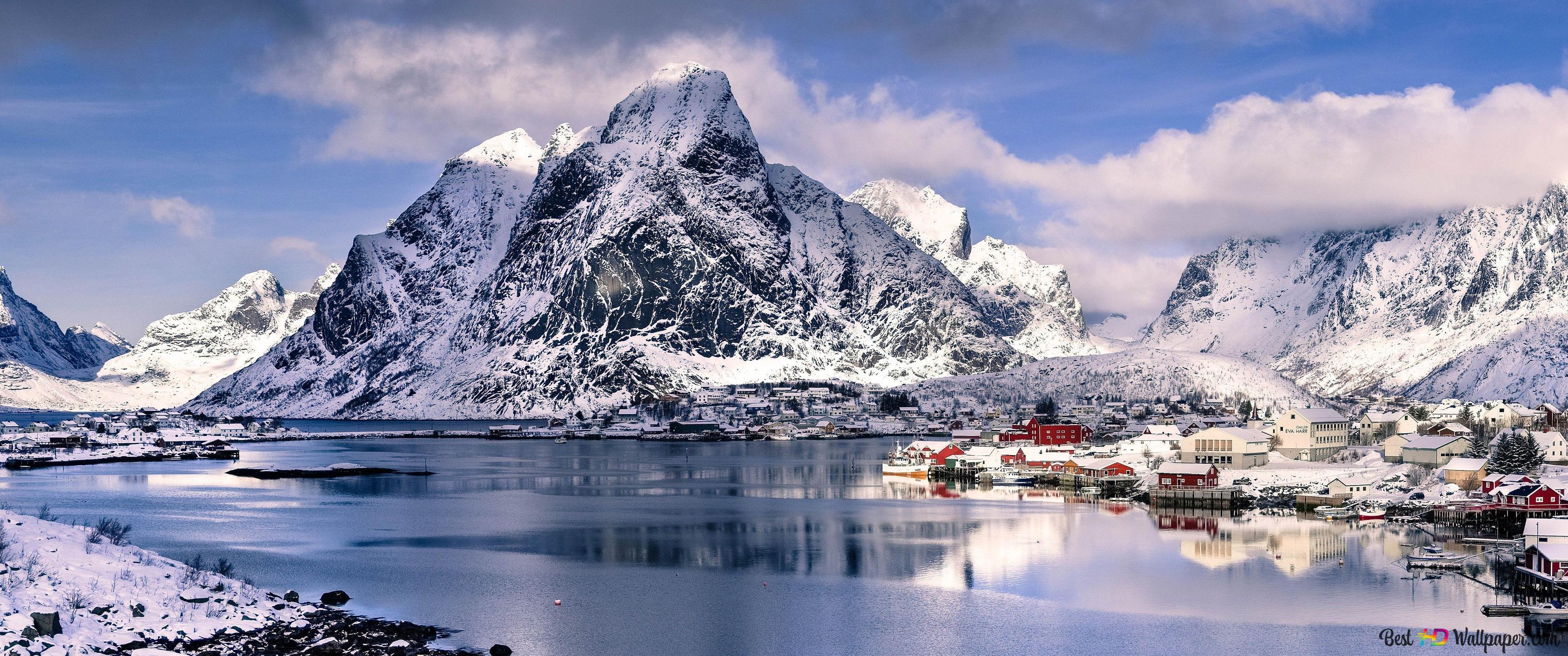 Snowy mountains, cloudy sky and town red houses reflected in lake water 4K wallpaper download