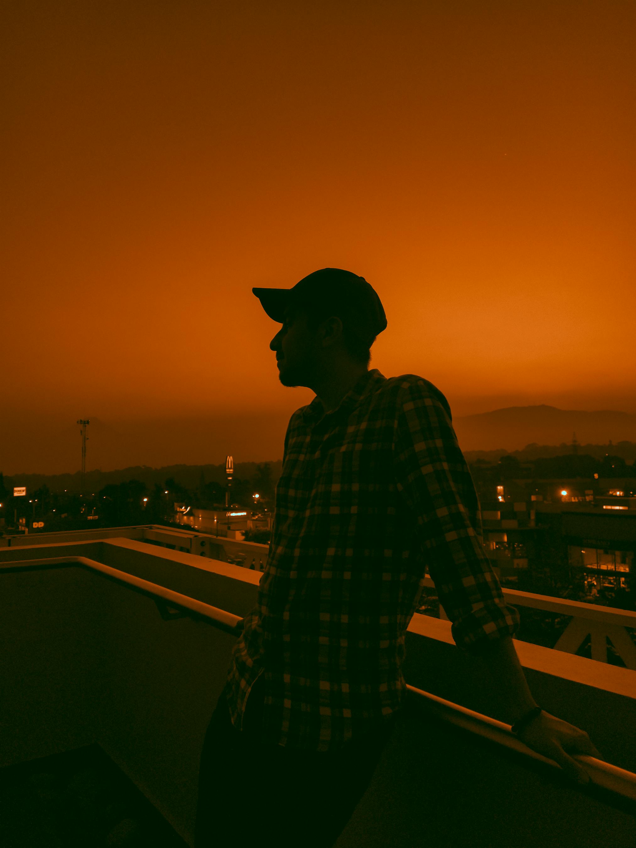 Silhouette of a Man Standing on the Rooftop at Sunset · Free