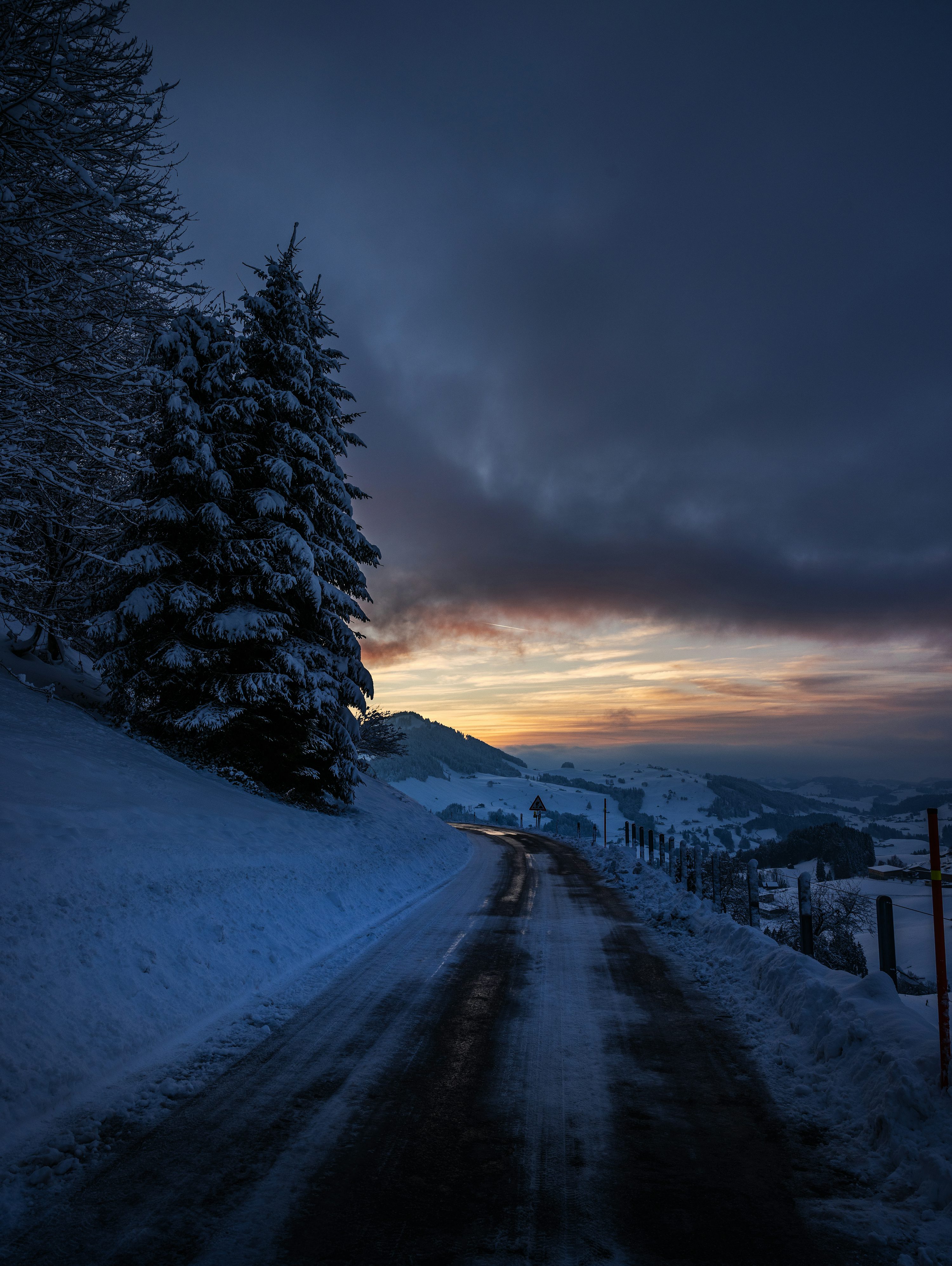 Snowy road through a winter landscape at dusk photo