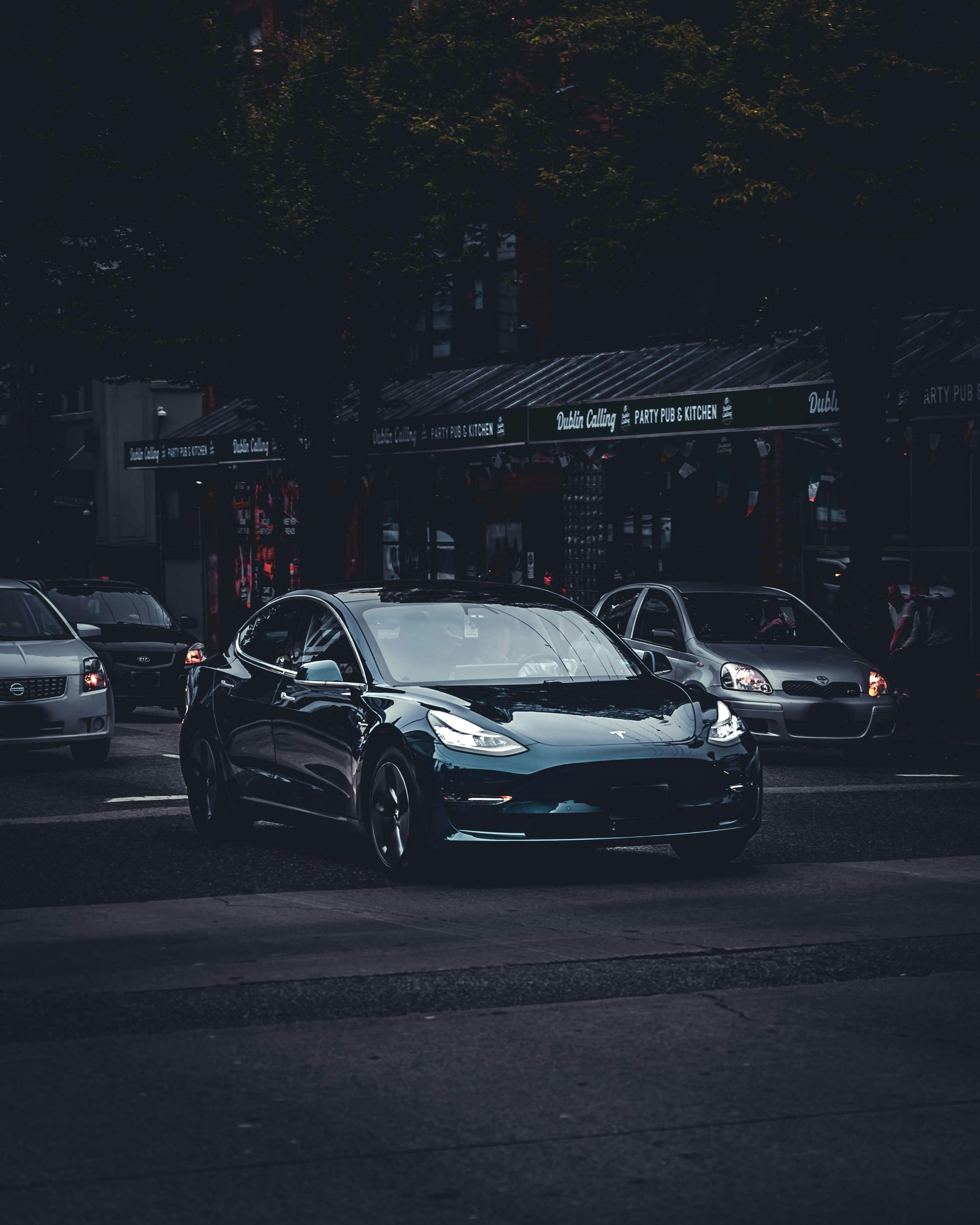 A black tesla model 3 is parked on the street · Free