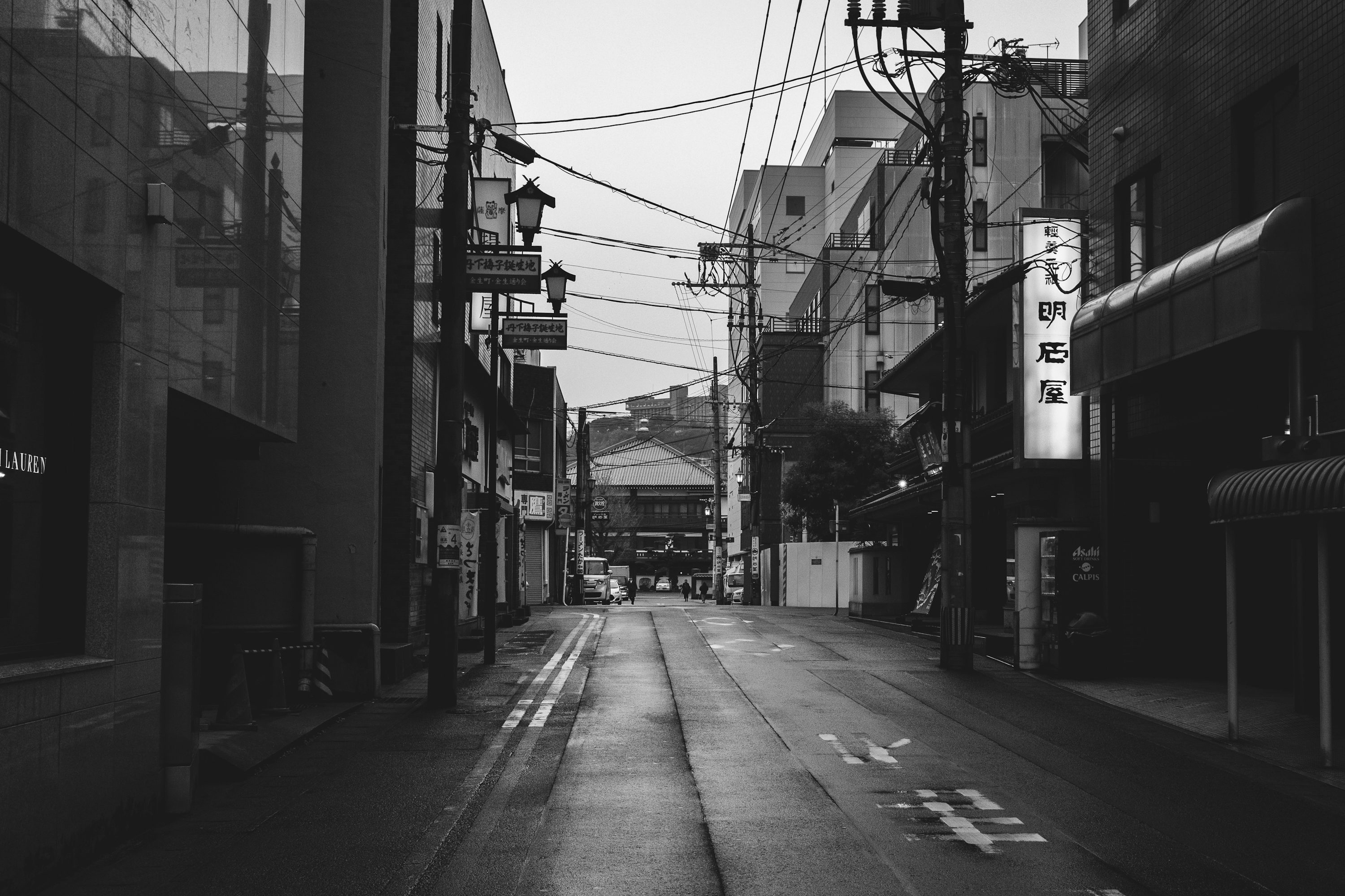 Grayscale photo of empty road between buildings photo
