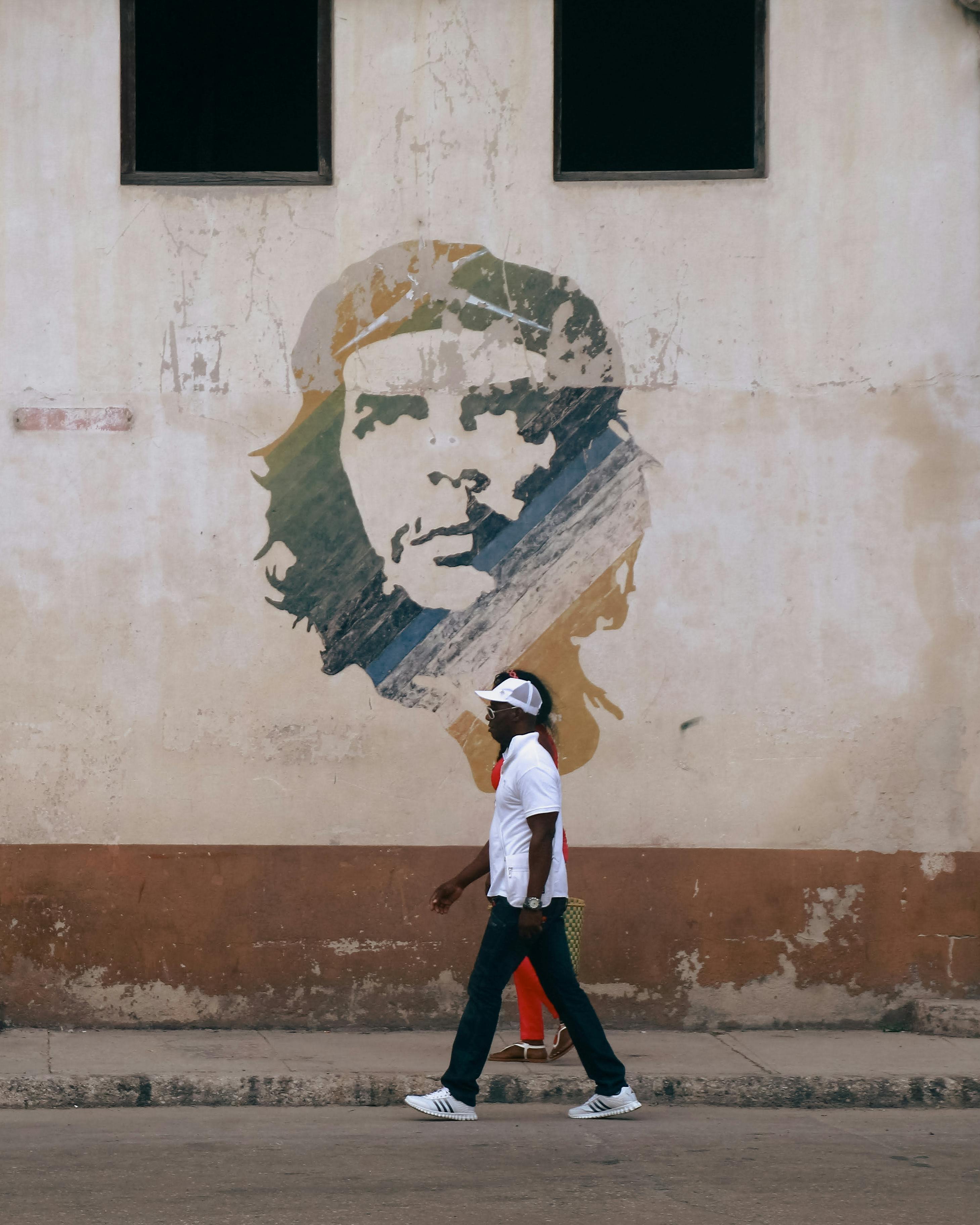 Man Passing Che Guevara Portrait Painted on Wall · Free
