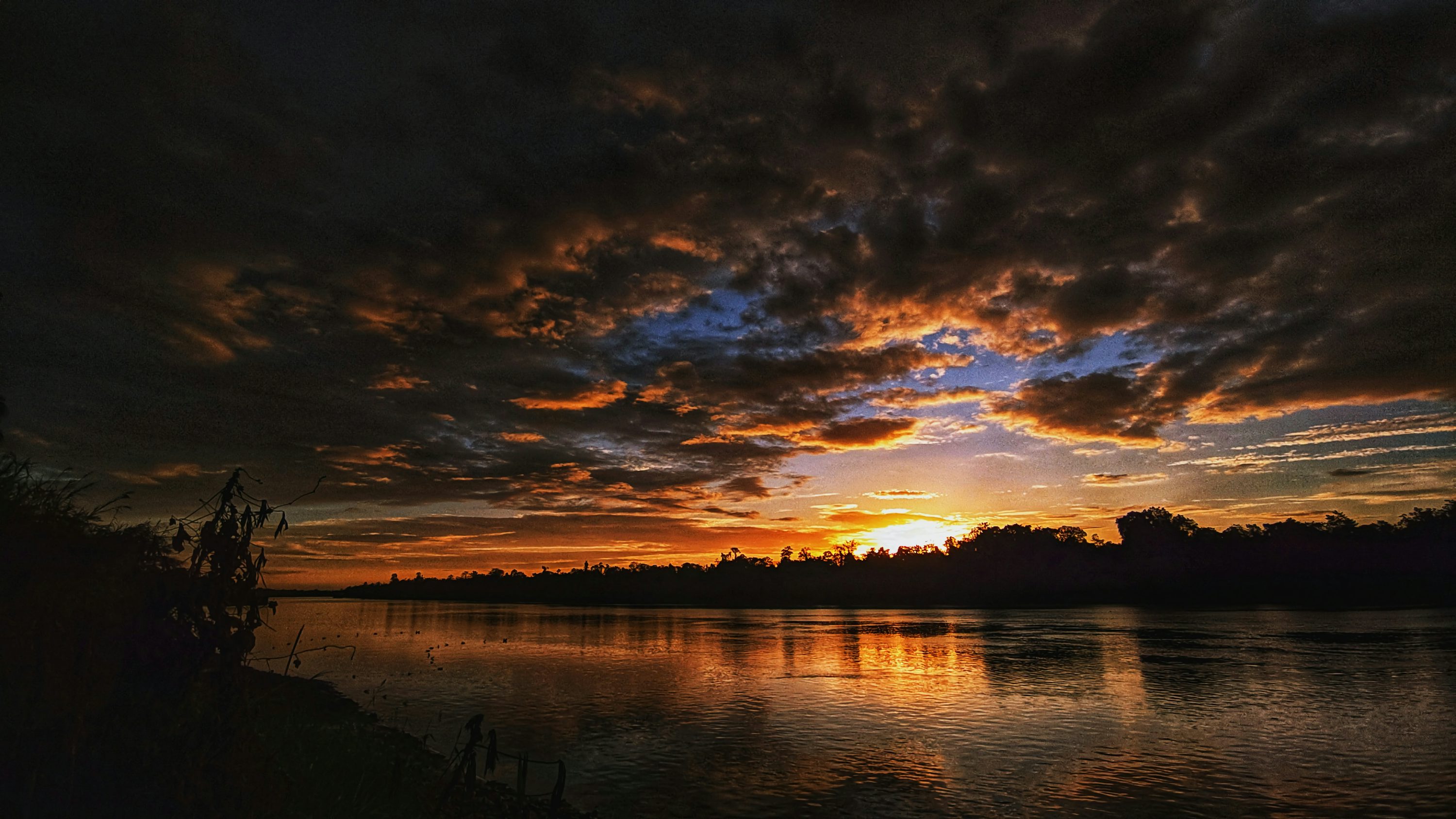 The sun is setting over the water and clouds photo