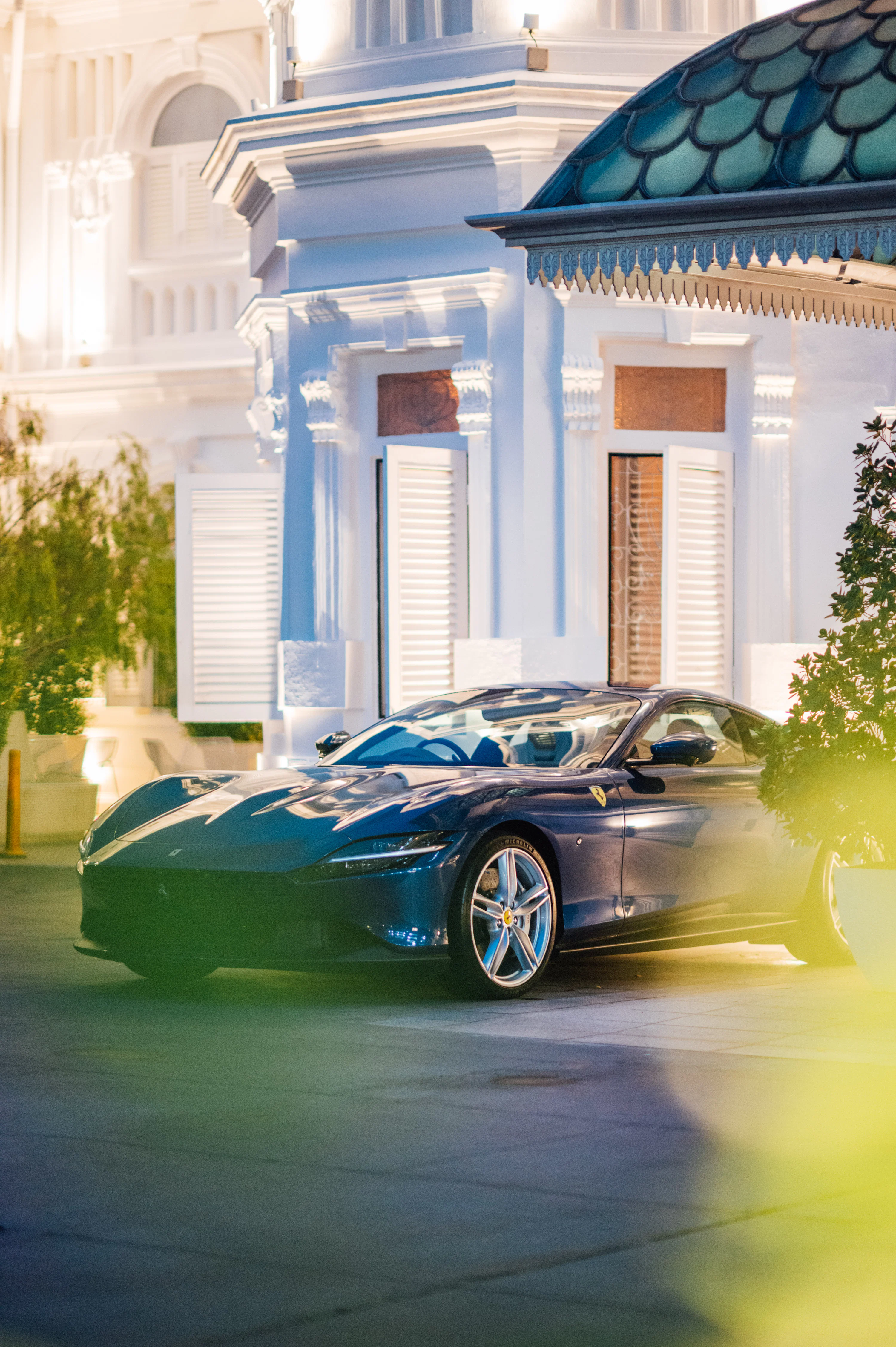 A blue sports car parked in front of a white building photo