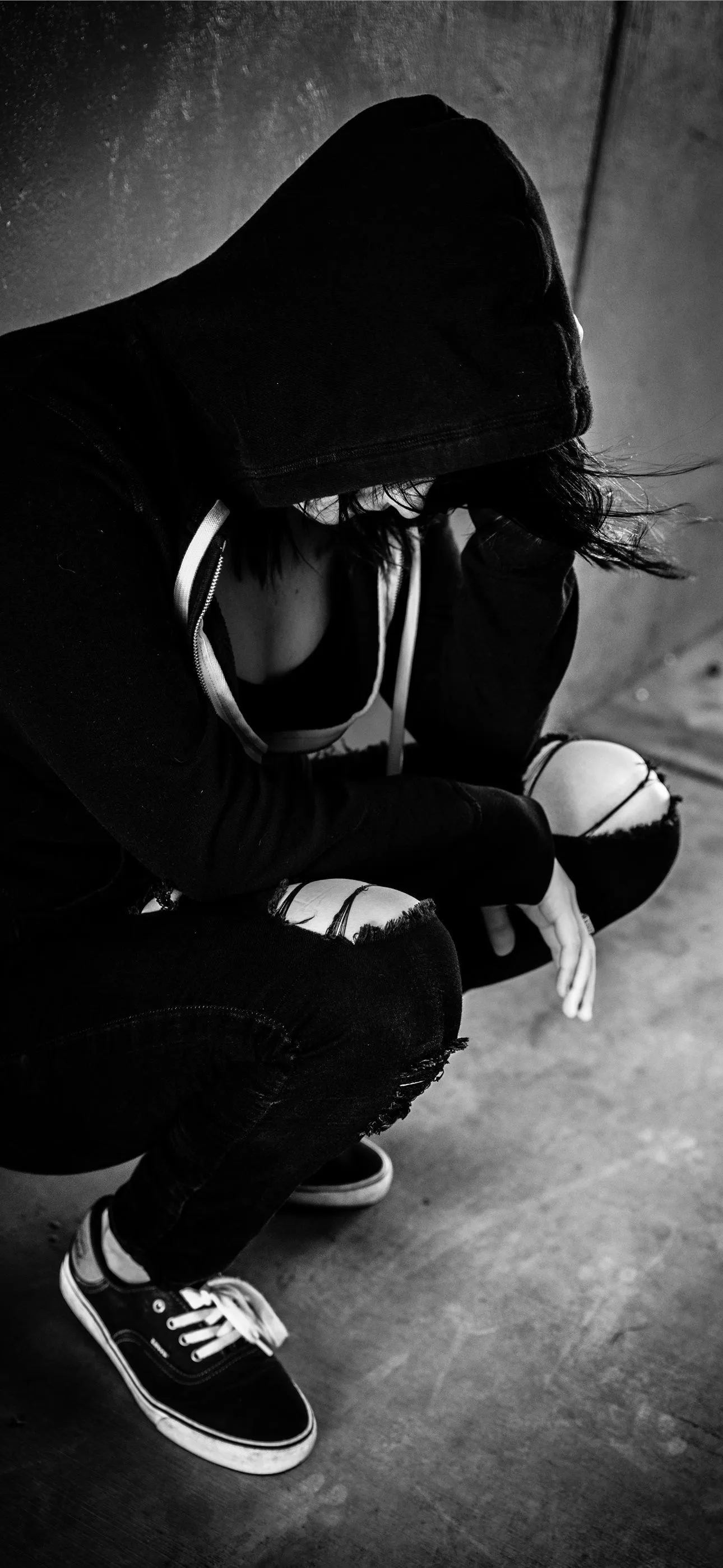 a woman sits alone against a wall holding her head iPhone Wallpaper Free Download