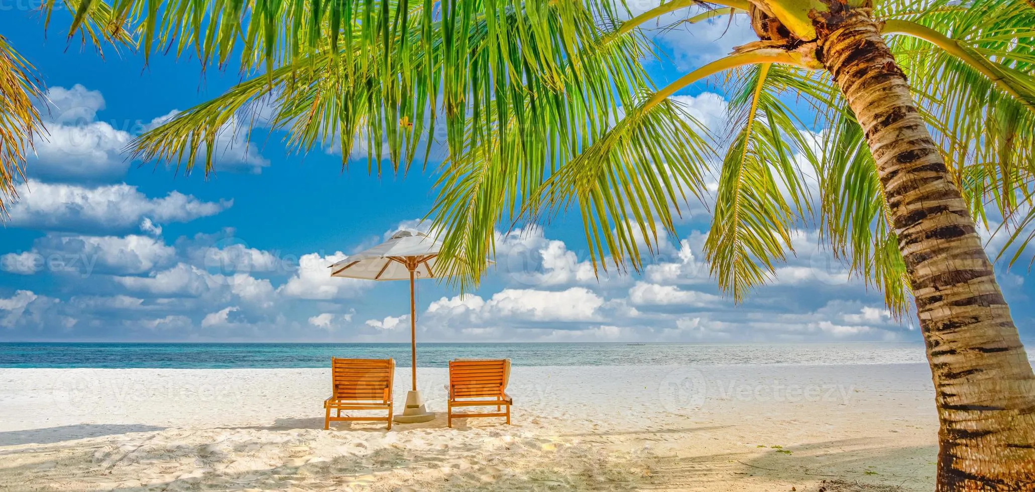 Beautiful tropical island scenery, two sun beds, loungers, umbrella under palm tree. White sand, sea view with horizon, idyllic blue sky, calmness and relaxation. Inspirational beach resort hotel 8009853