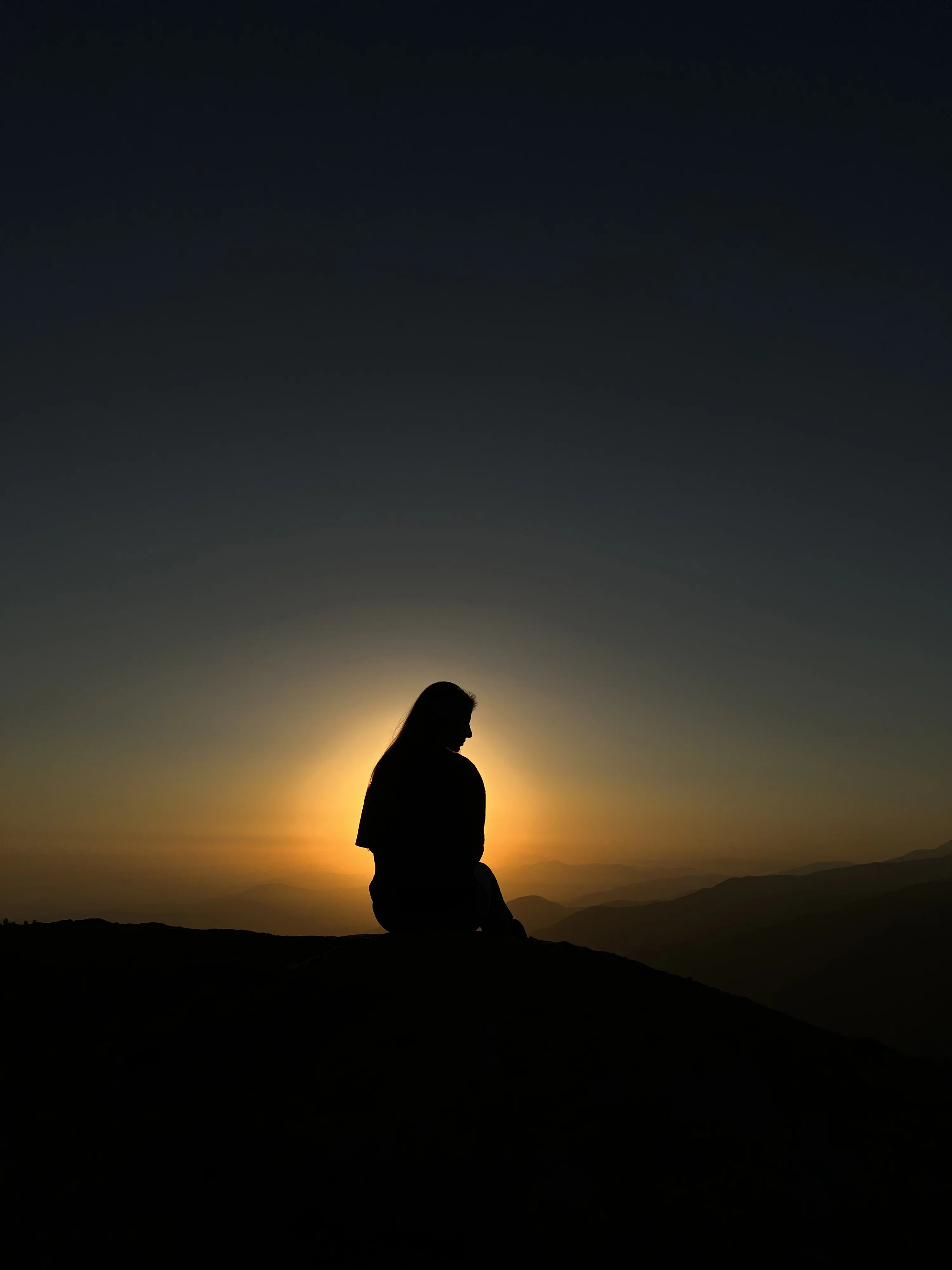 A person sitting on top of a hill at sunset photo