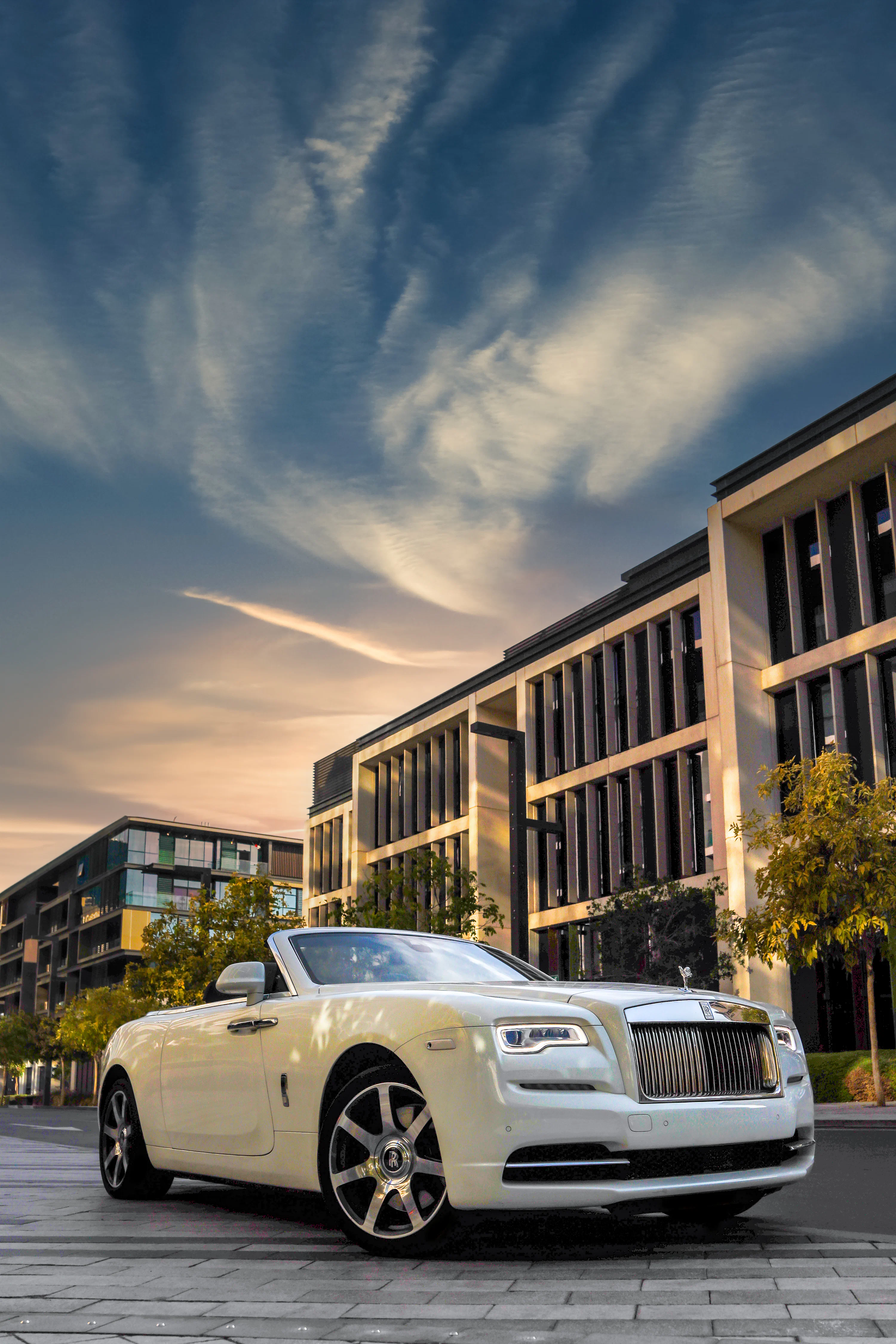 A white rolls royce parked in front of a building photo