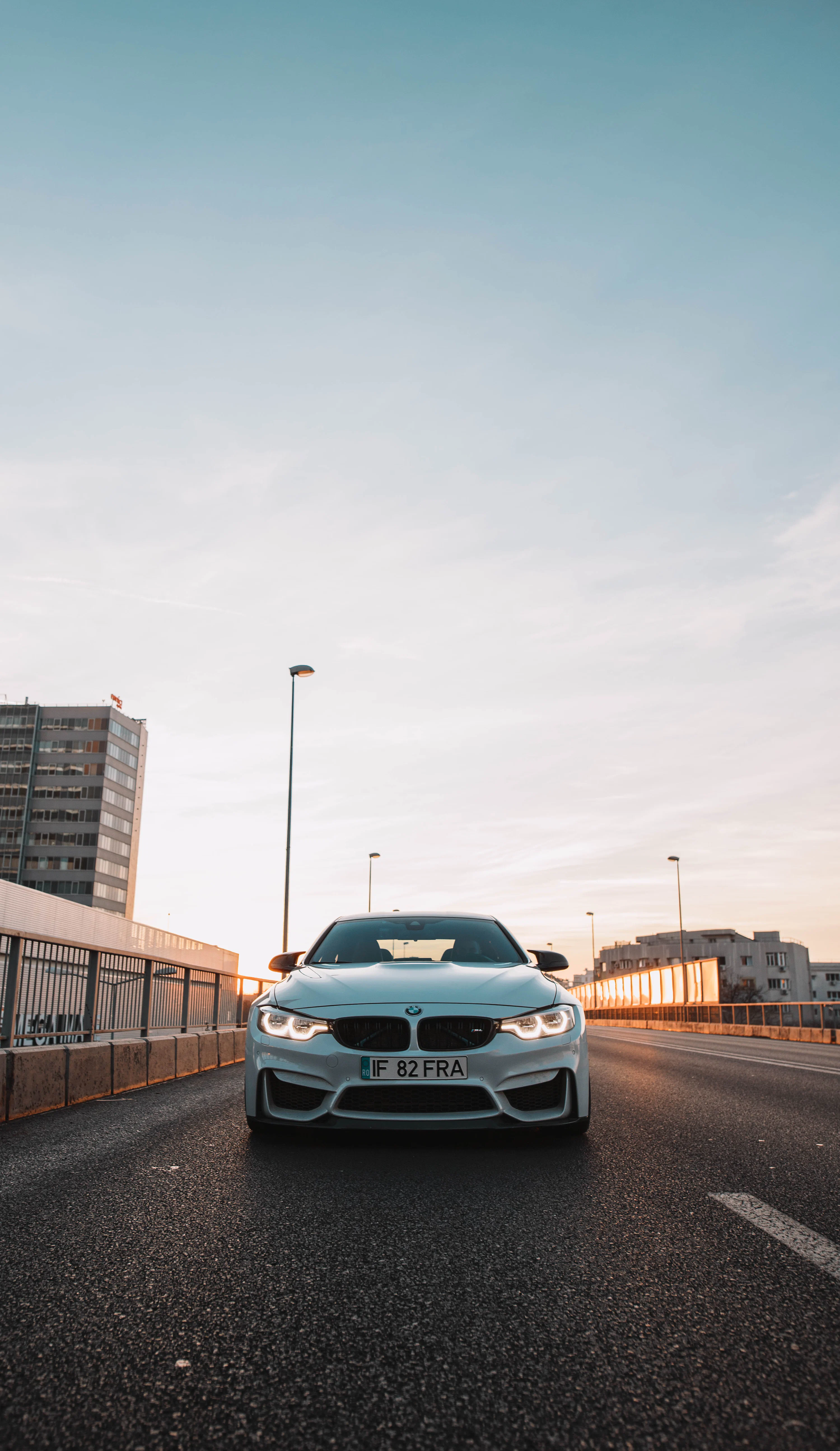 A white car driving down a street next to tall buildings photo