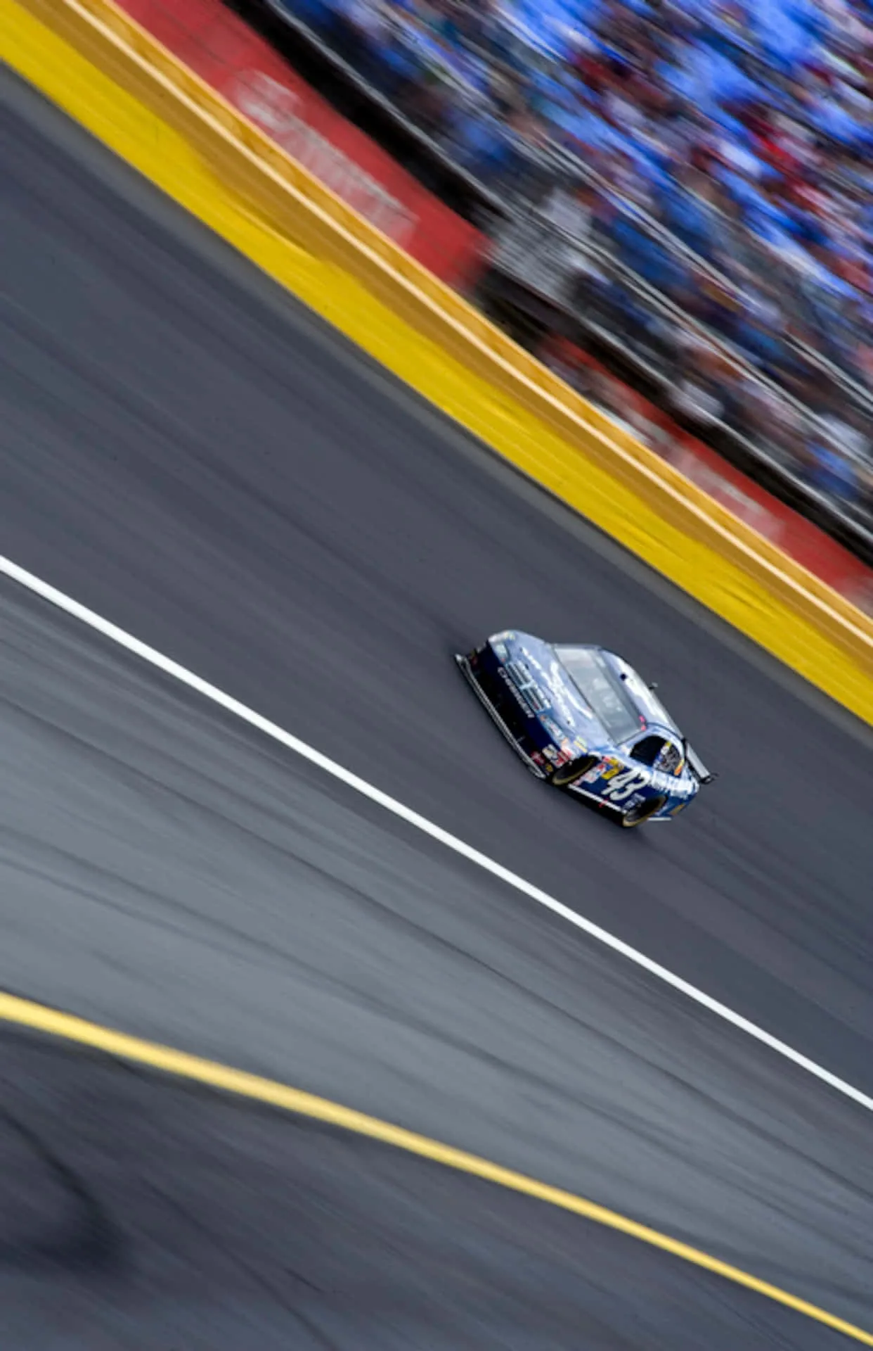Download A Nascar Car Is Driving On A Track Wallpaper