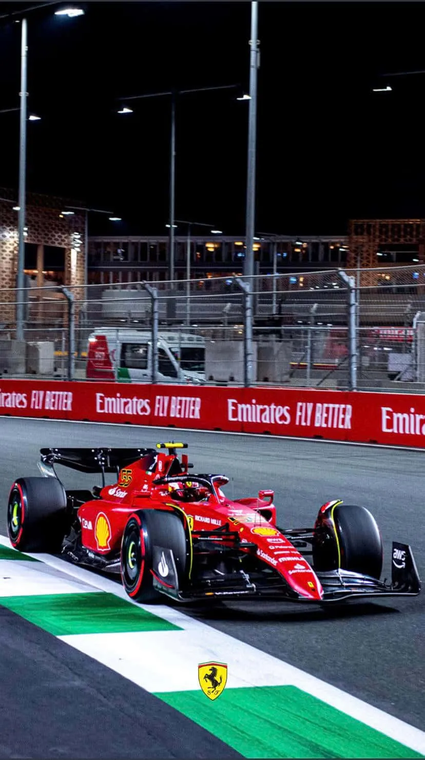 Download A Ferrari Racing Car Driving On A Track At Night Wallpaper