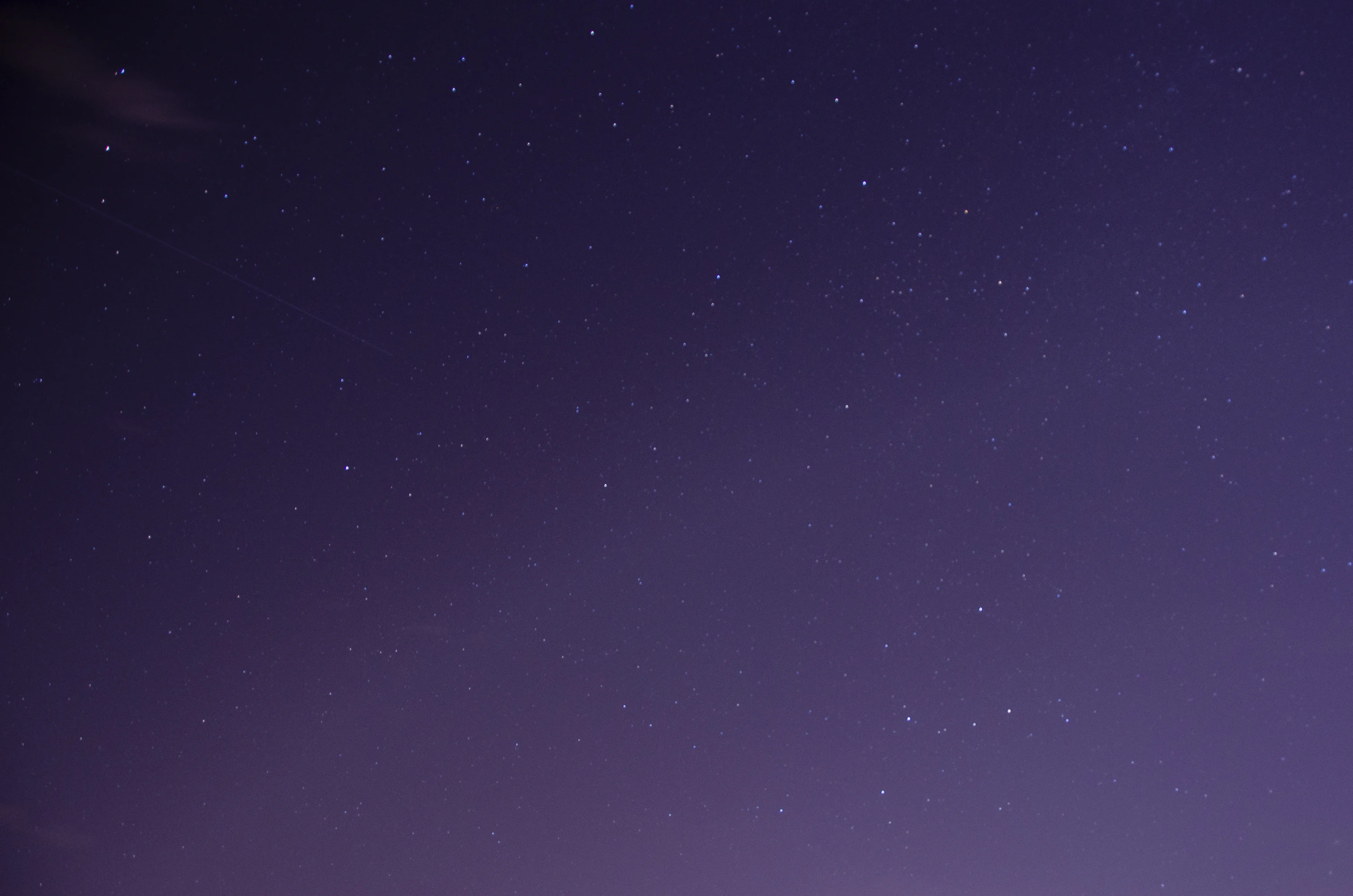 A night sky with stars and a plane in the distance photo