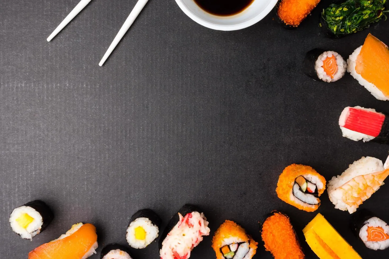 Top view of Sushi set with chopsticks and sauce on black background, Japanese food. Free space for text