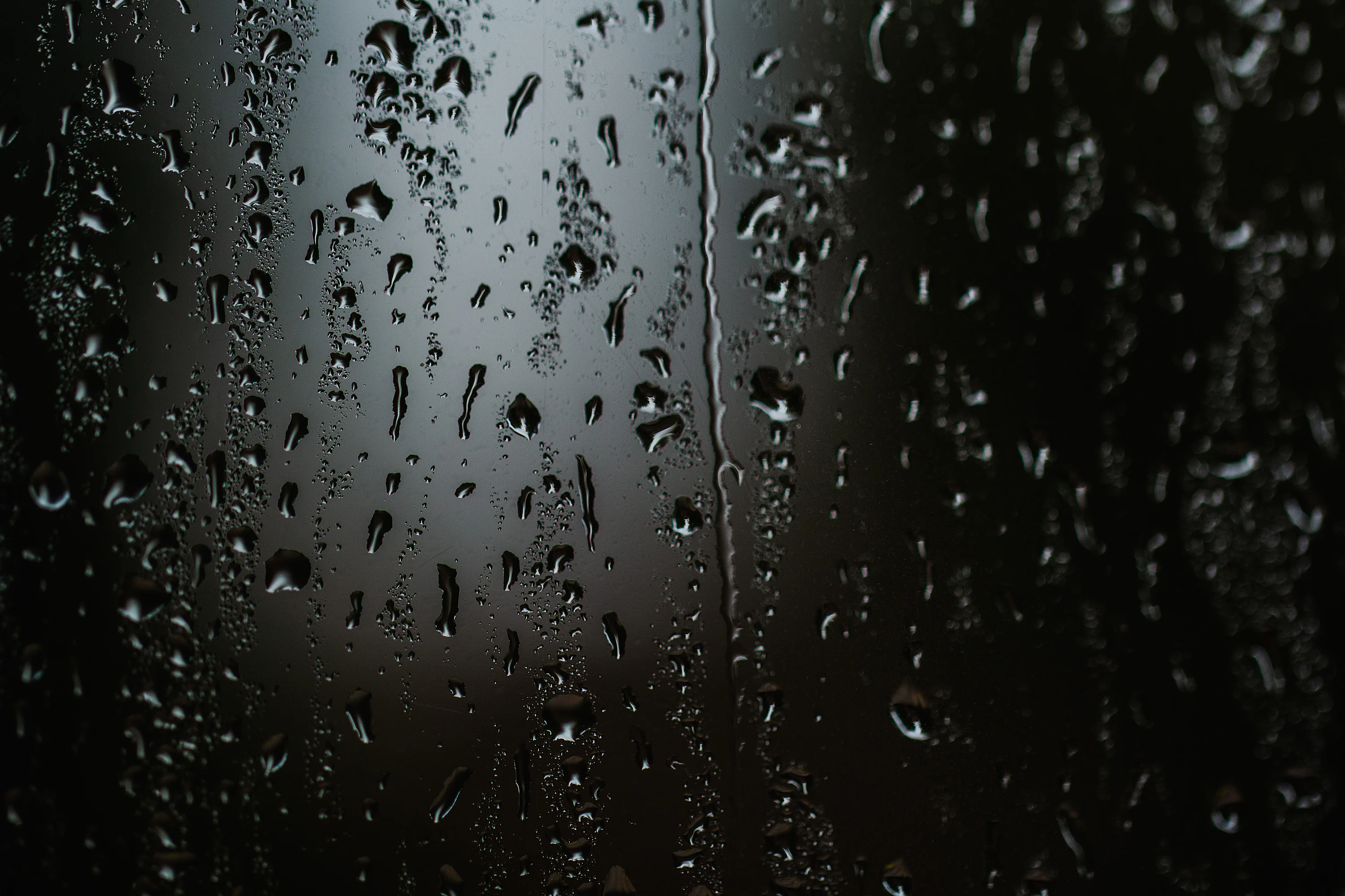 Rain drops on a window with a black background photo