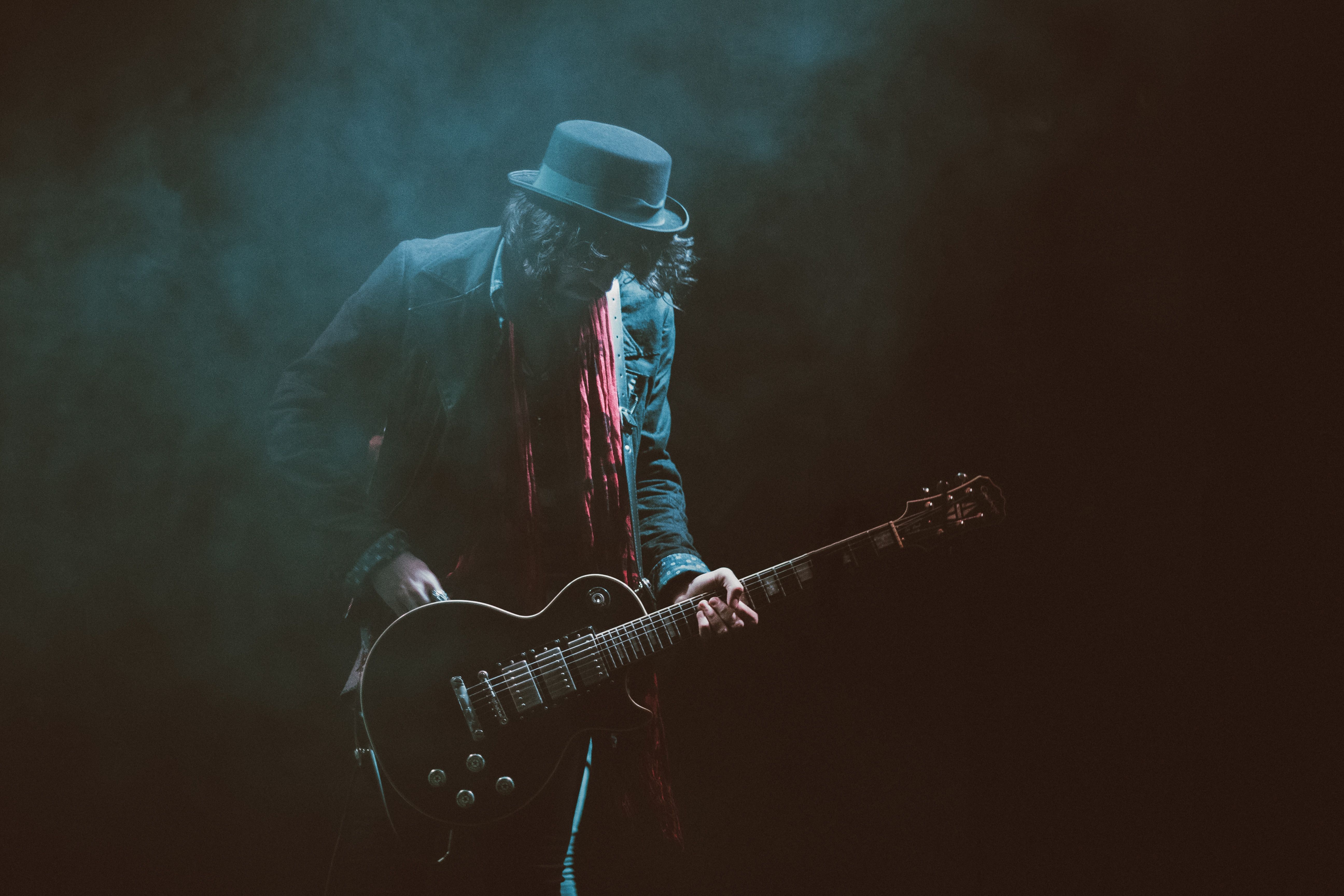 man in black hat playing black electric guitar free image