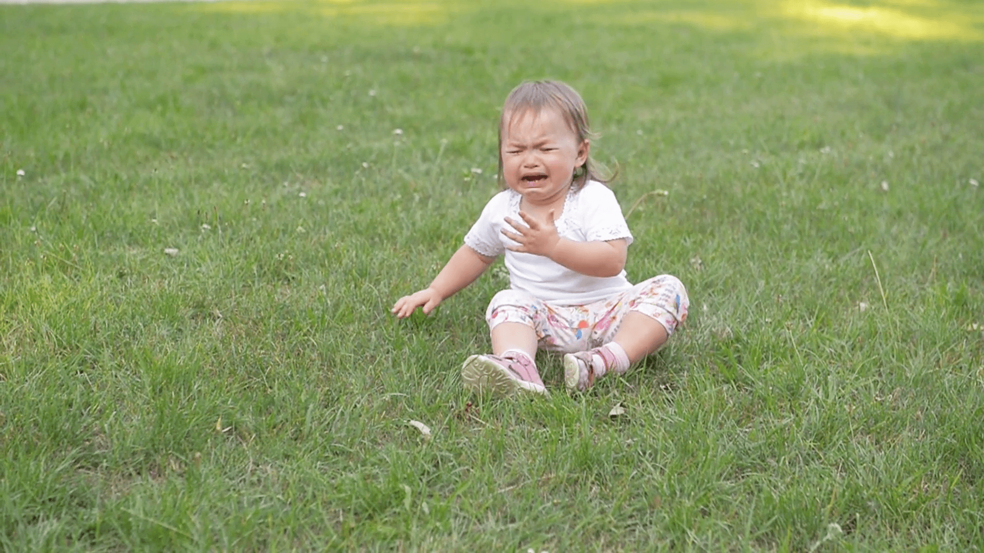 Children crying on green grass background, Small baby girl