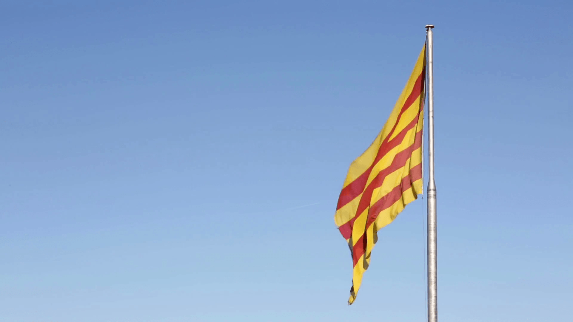 Catalan flag in Catalonia, Barcelona, Spain waving against blue
