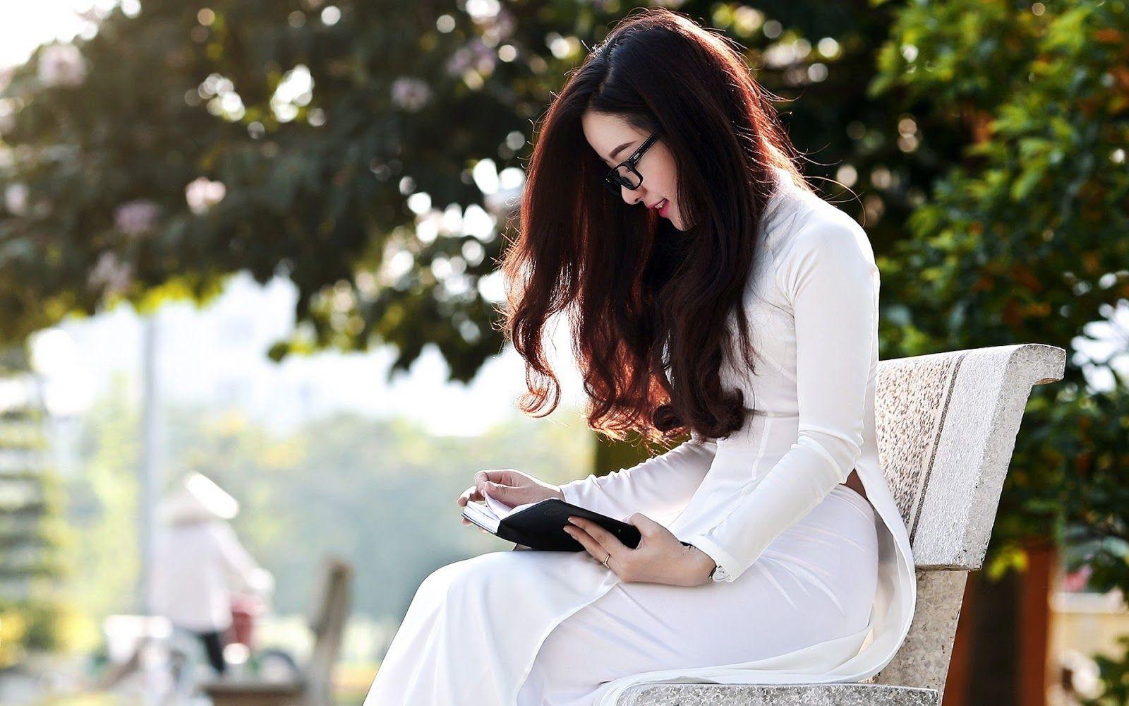 Beautiful Glassy Vietnamese Girl wear Ao Dai reading a book