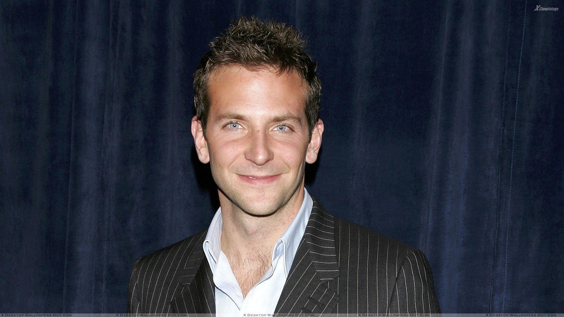 Bradley Cooper Smiling In Black Coat N Blue Background Wallpaper