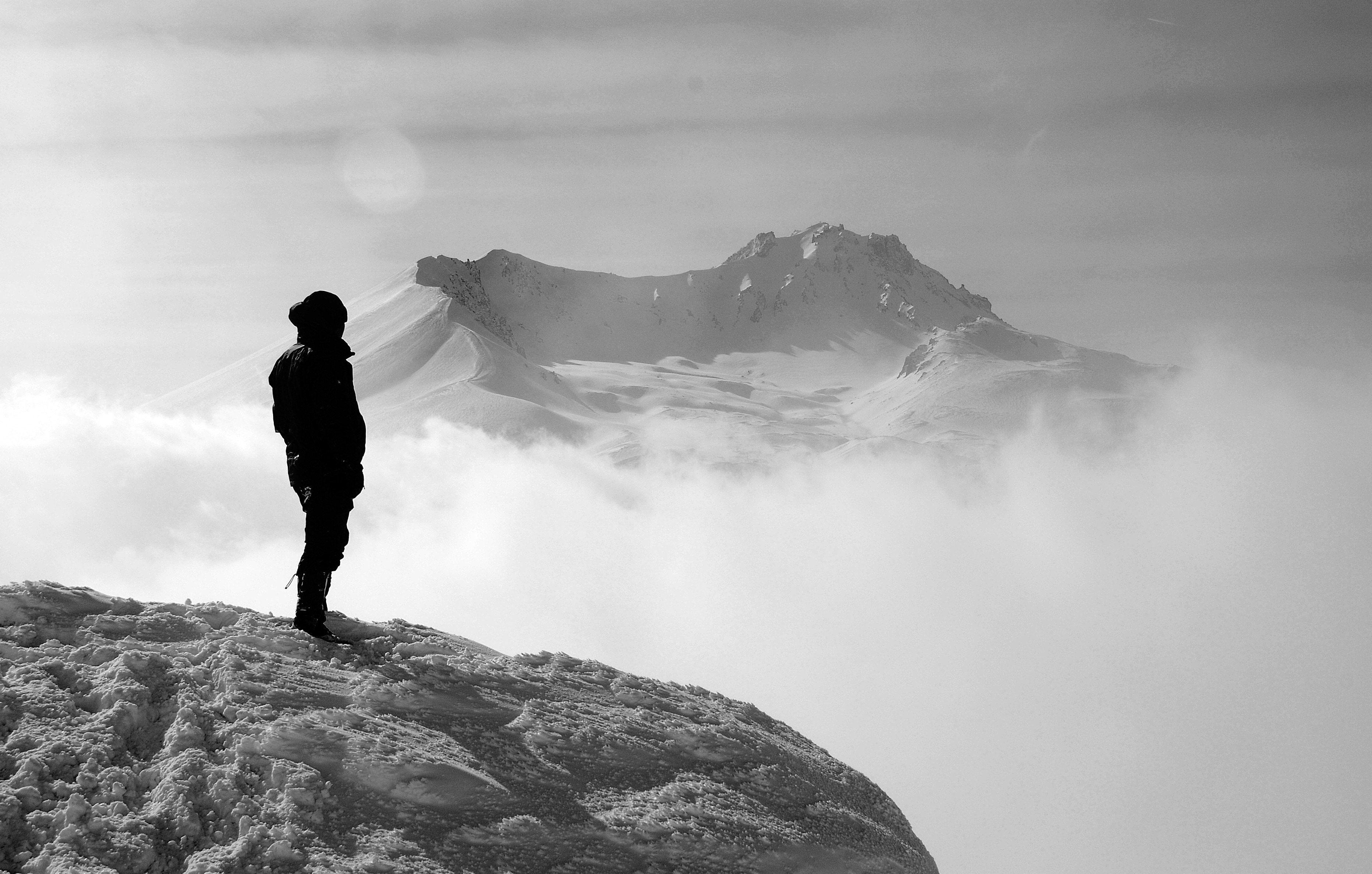 silhouette of person standing while facing the alps free image
