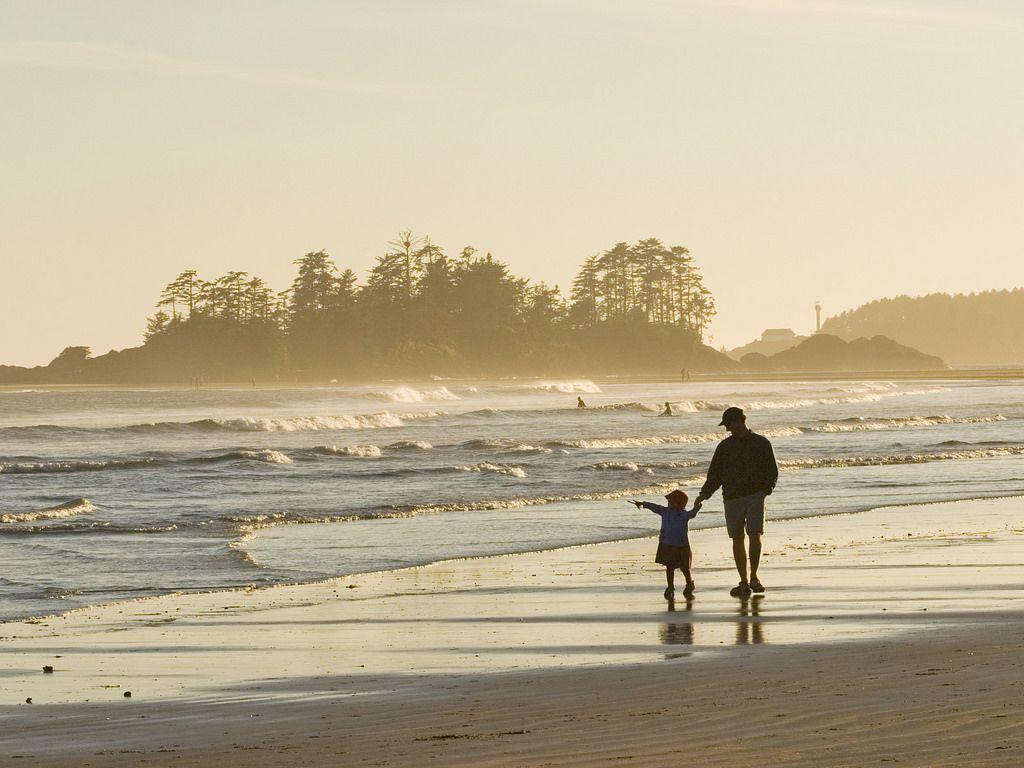 Father & daughter walk along beach. Tofino, BC, Canada