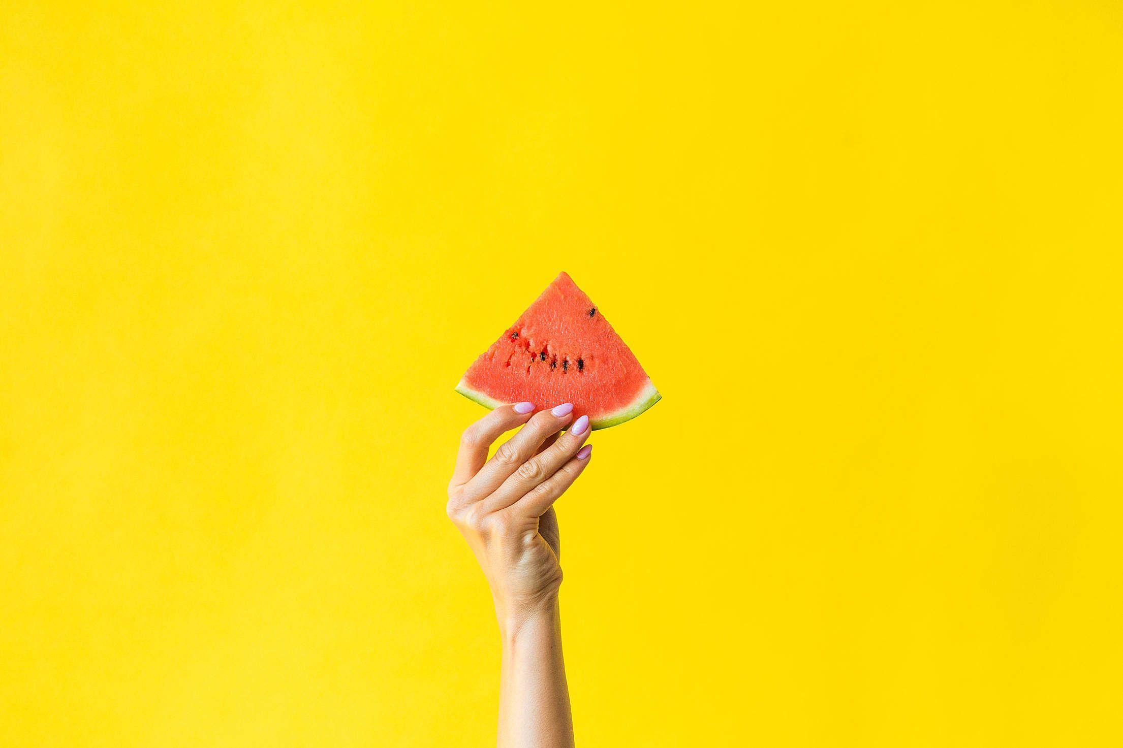 Slice of Watermelon in Woman Hand on Bright Yellow Background Free