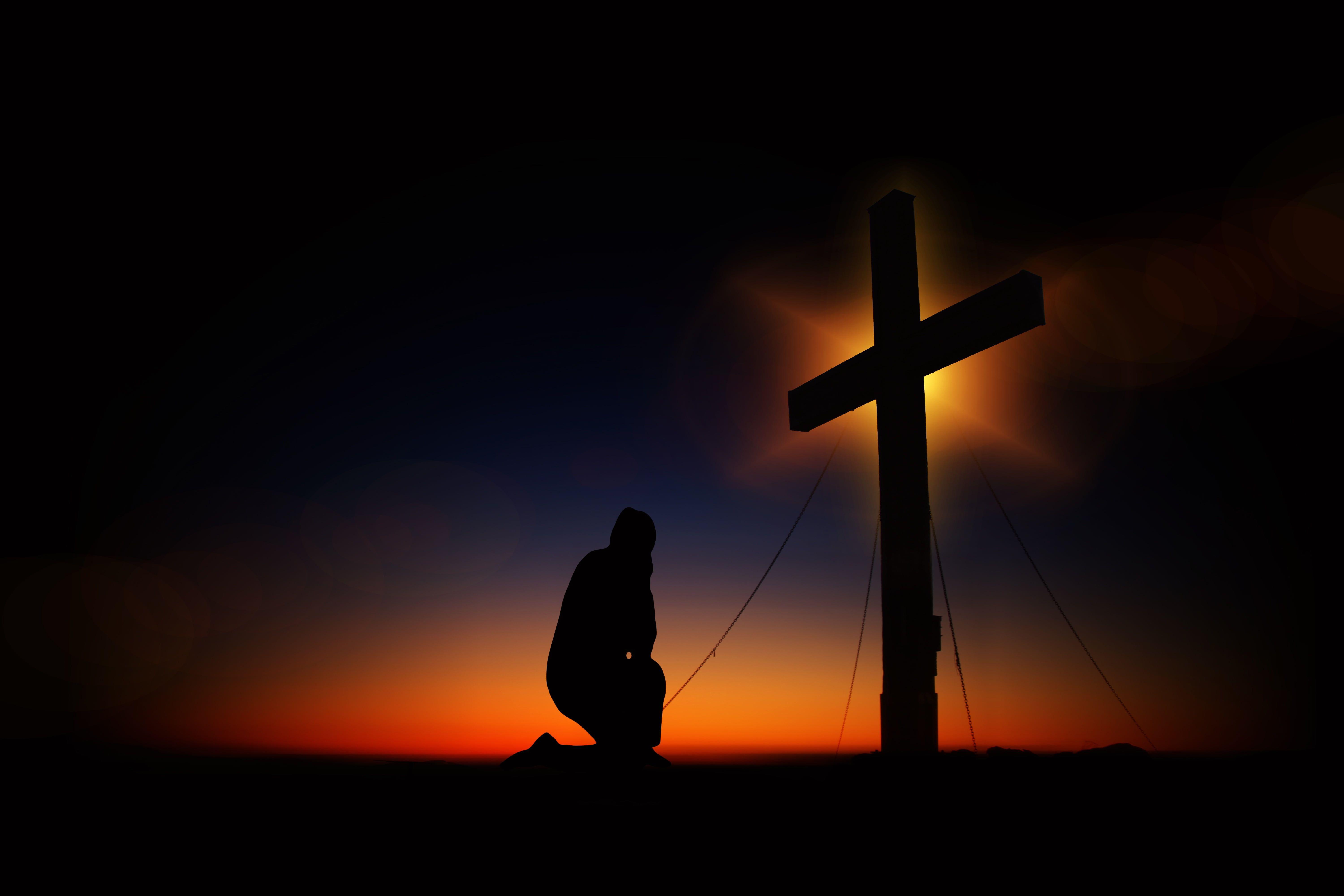 Silhouette photograph of man kneeling in front of the cross HD