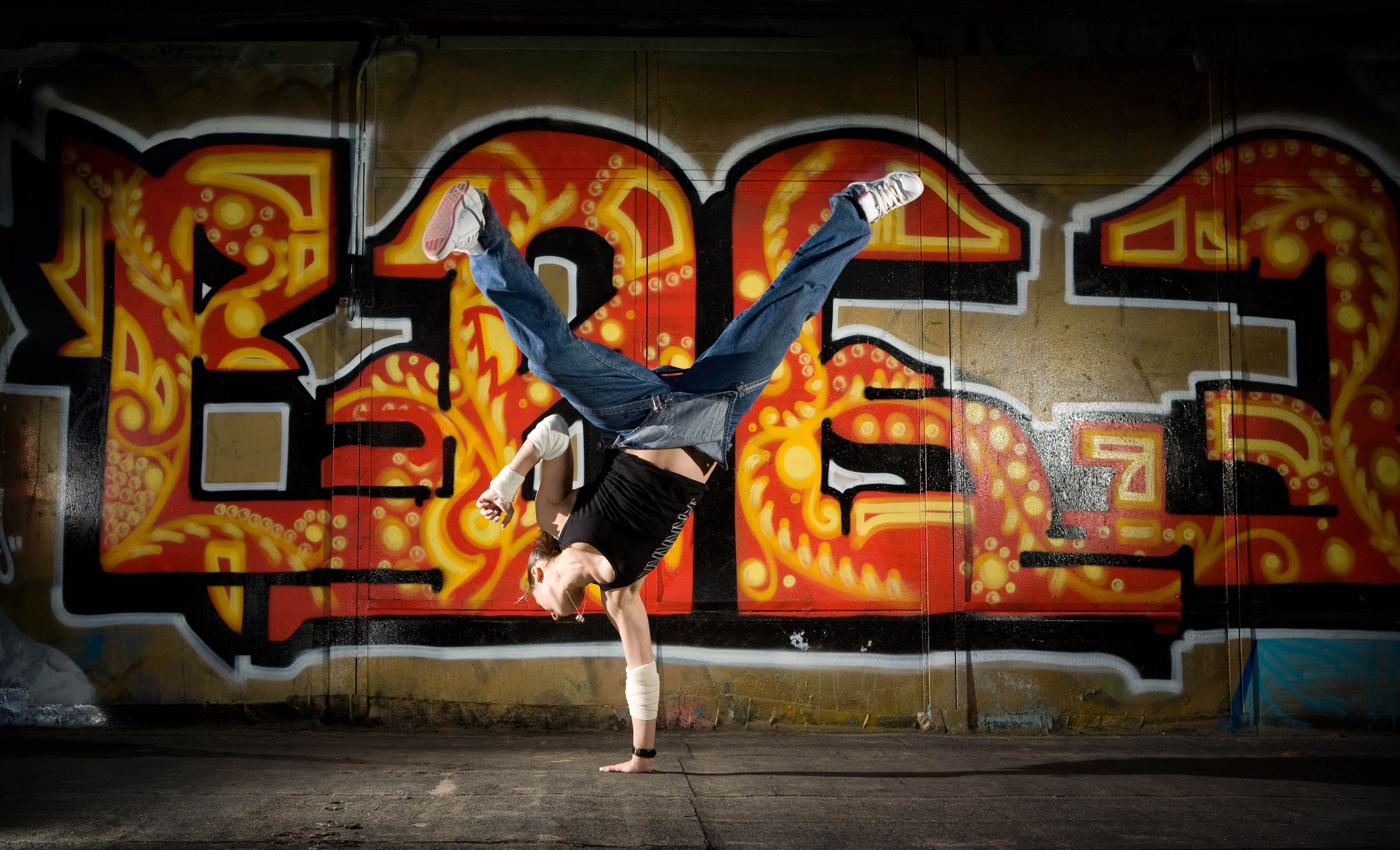 Person break dancing near graffiti painted wall HD wallpaper