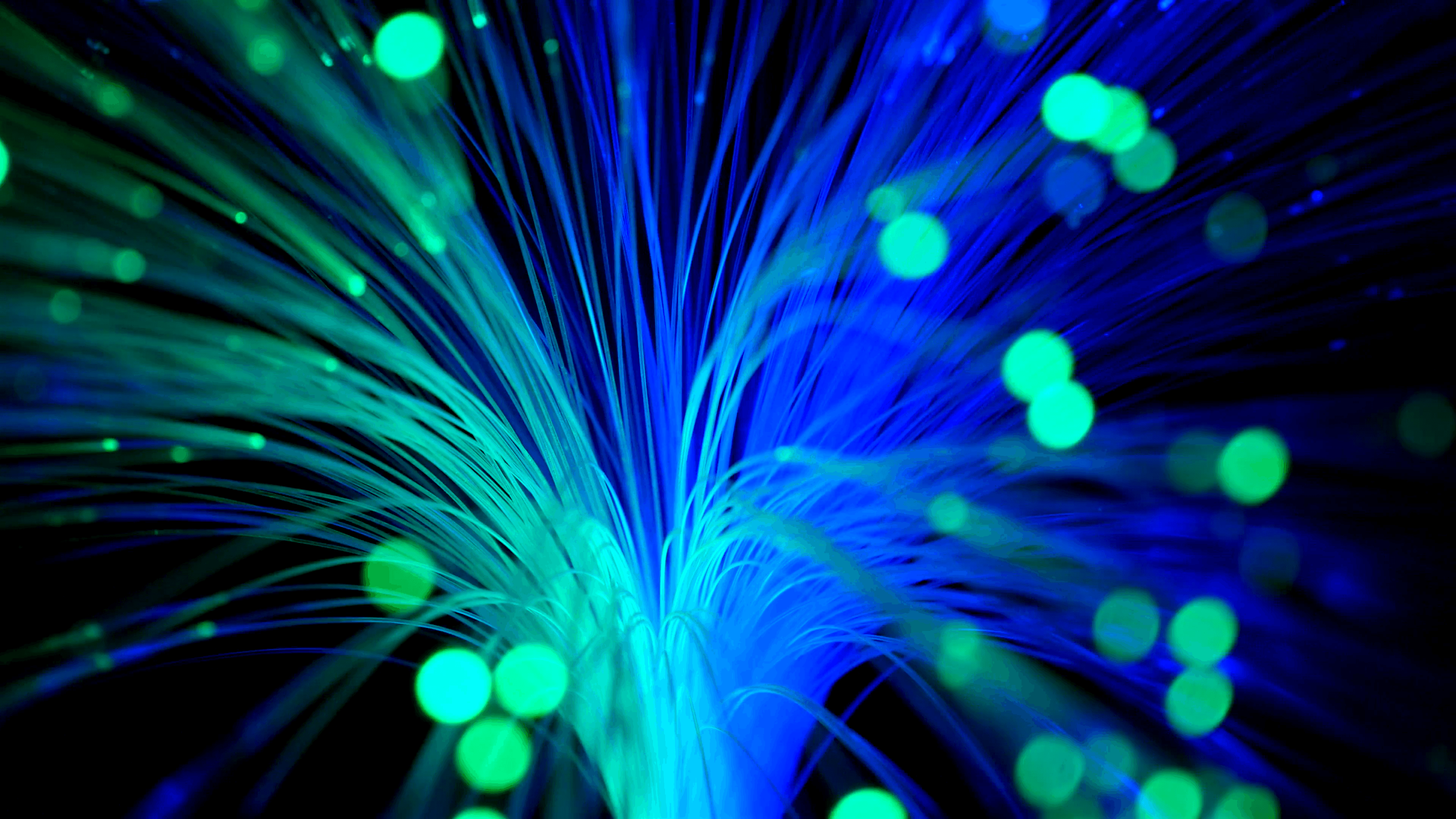 Green and blue fiber optics strands moving against a black
